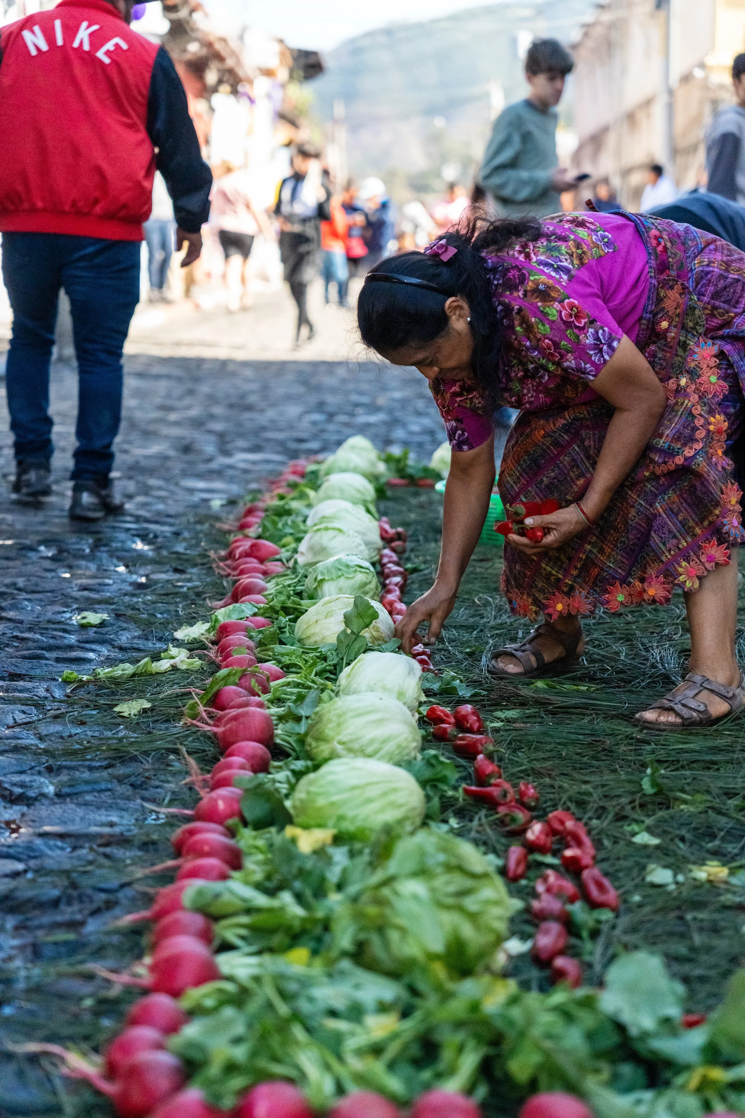Femme en huipil disposant une ligne de radis, choux et légumes