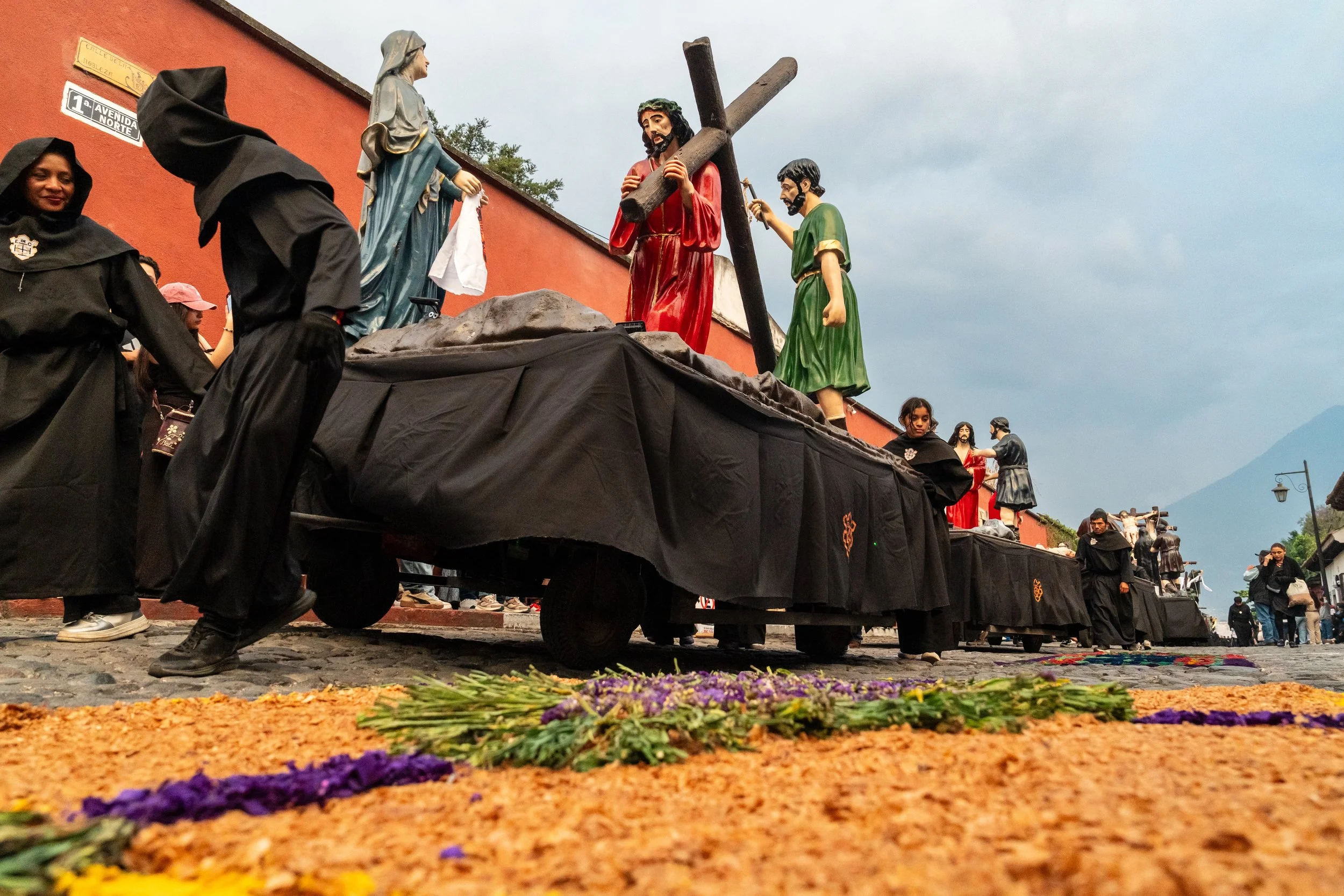 L'anda drapée de noir (Jésus portant la croix) avançant sur la sciure ocre semée de fleurs violettes