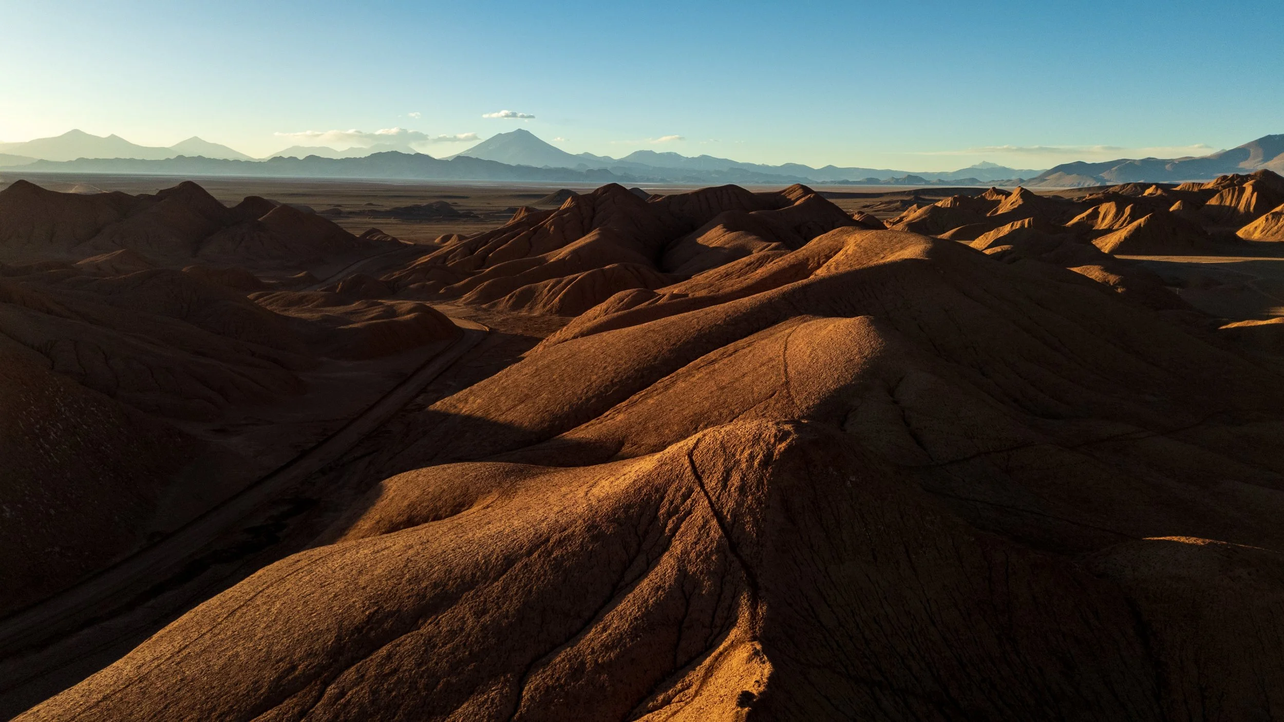 Photo aérienne au drone de dunes érodées au lever du soleil avec des volcans à l'horizon