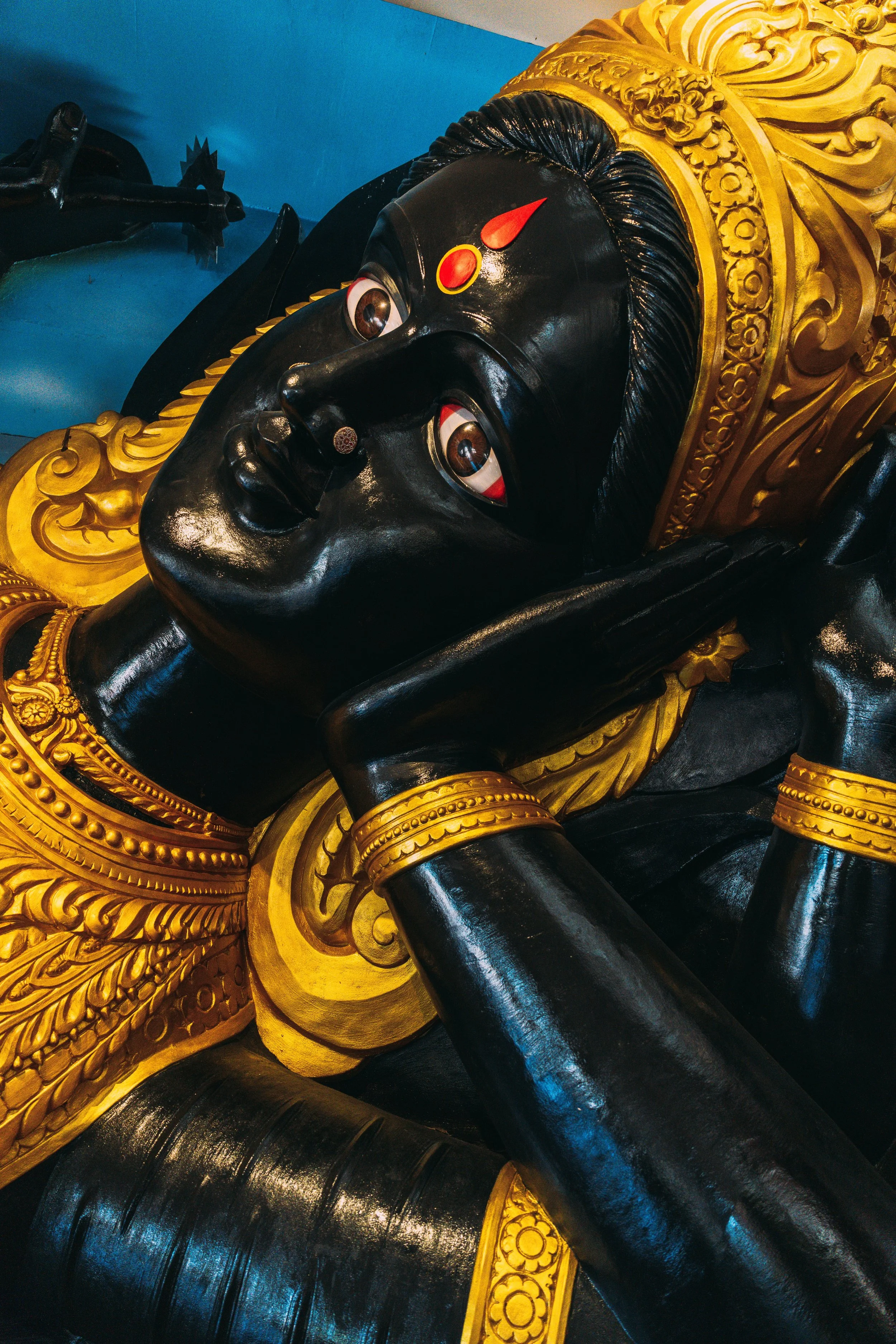 Gros plan sur une statue noire ornée d'ornements dorés dans le temple de Batu Caves