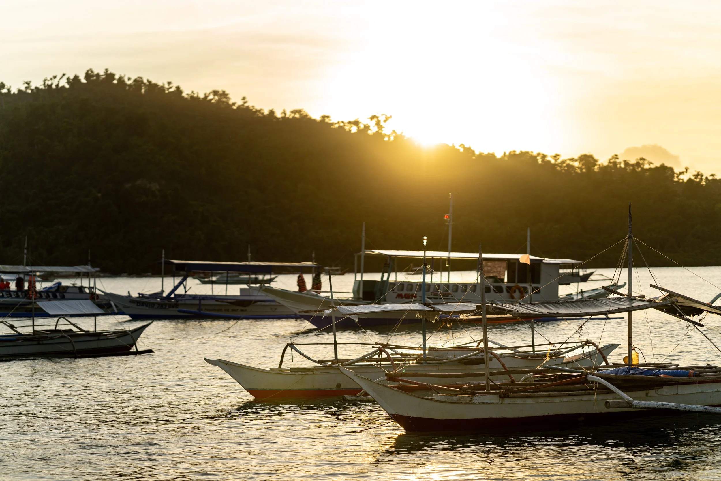 Bancas amarrées au coucher du soleil sur la plage de Port Barton