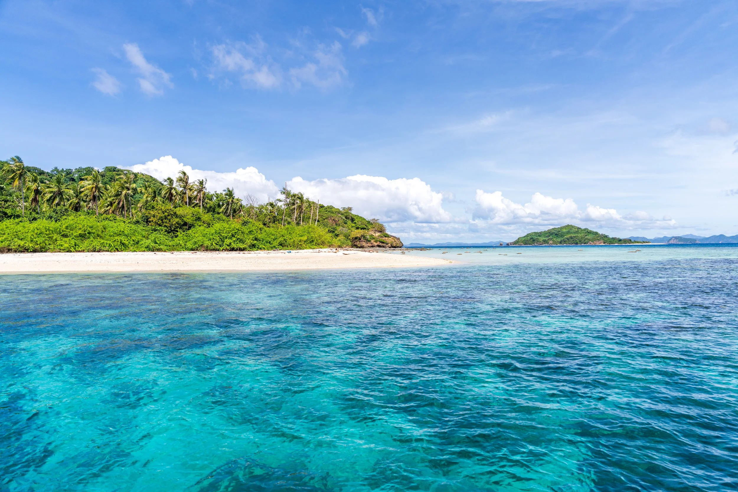 Plage de sable blanc et eaux turquoise d'un îlot entre El Nido et Coron aux Philippines