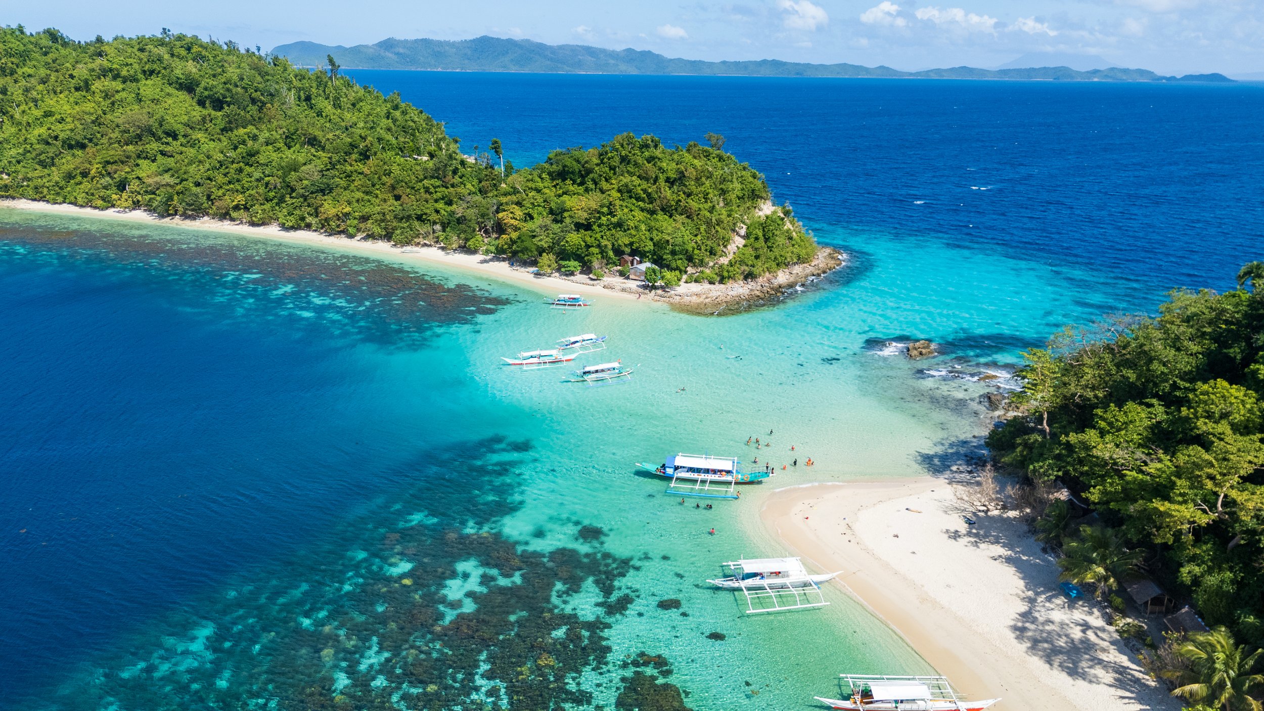 Îlot et récifs turquoise lors d'une sortie island hopping à Port Barton