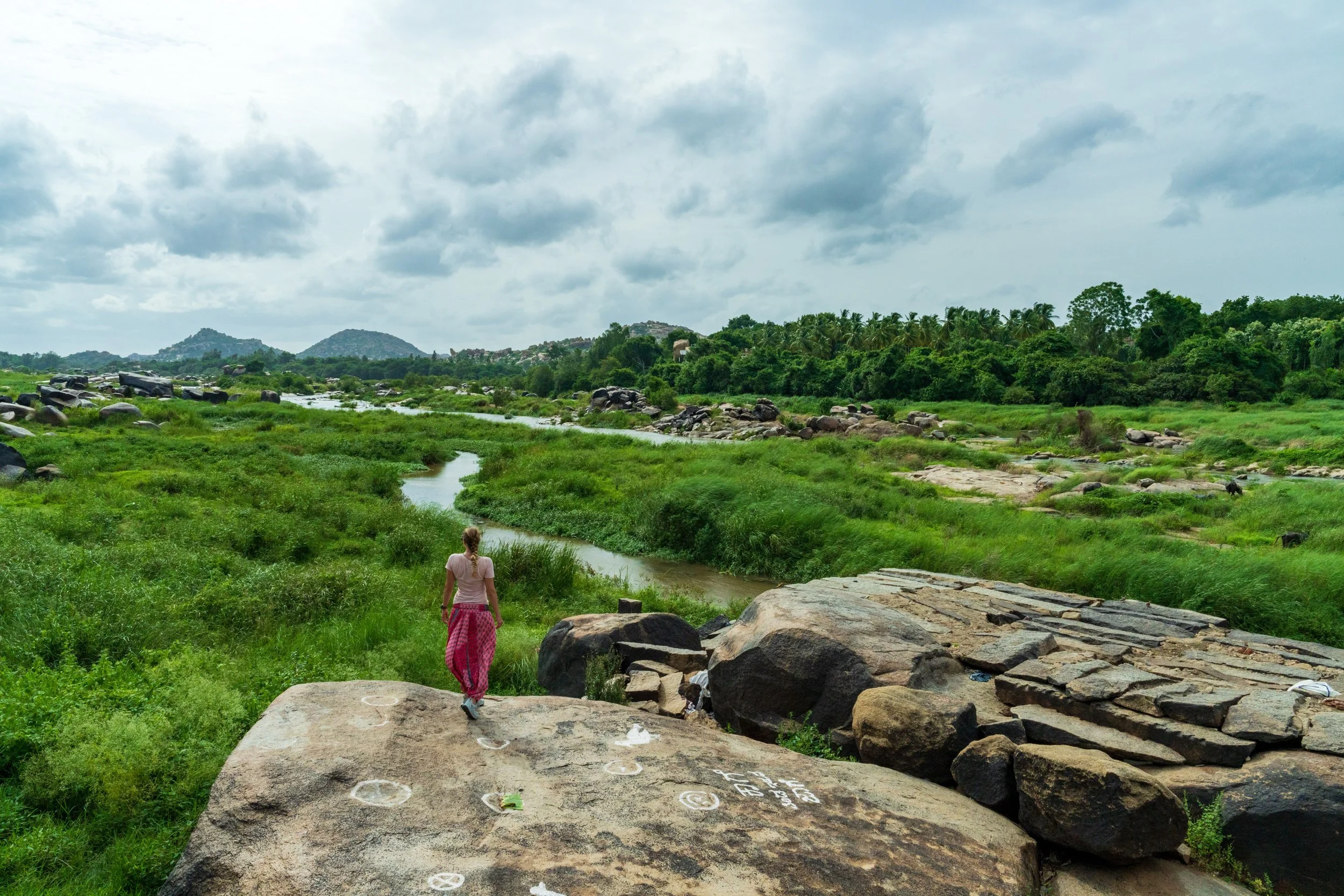 Femme en sari marchant sur les rochers au bord de la rivière Tungabhadra à Hampi
