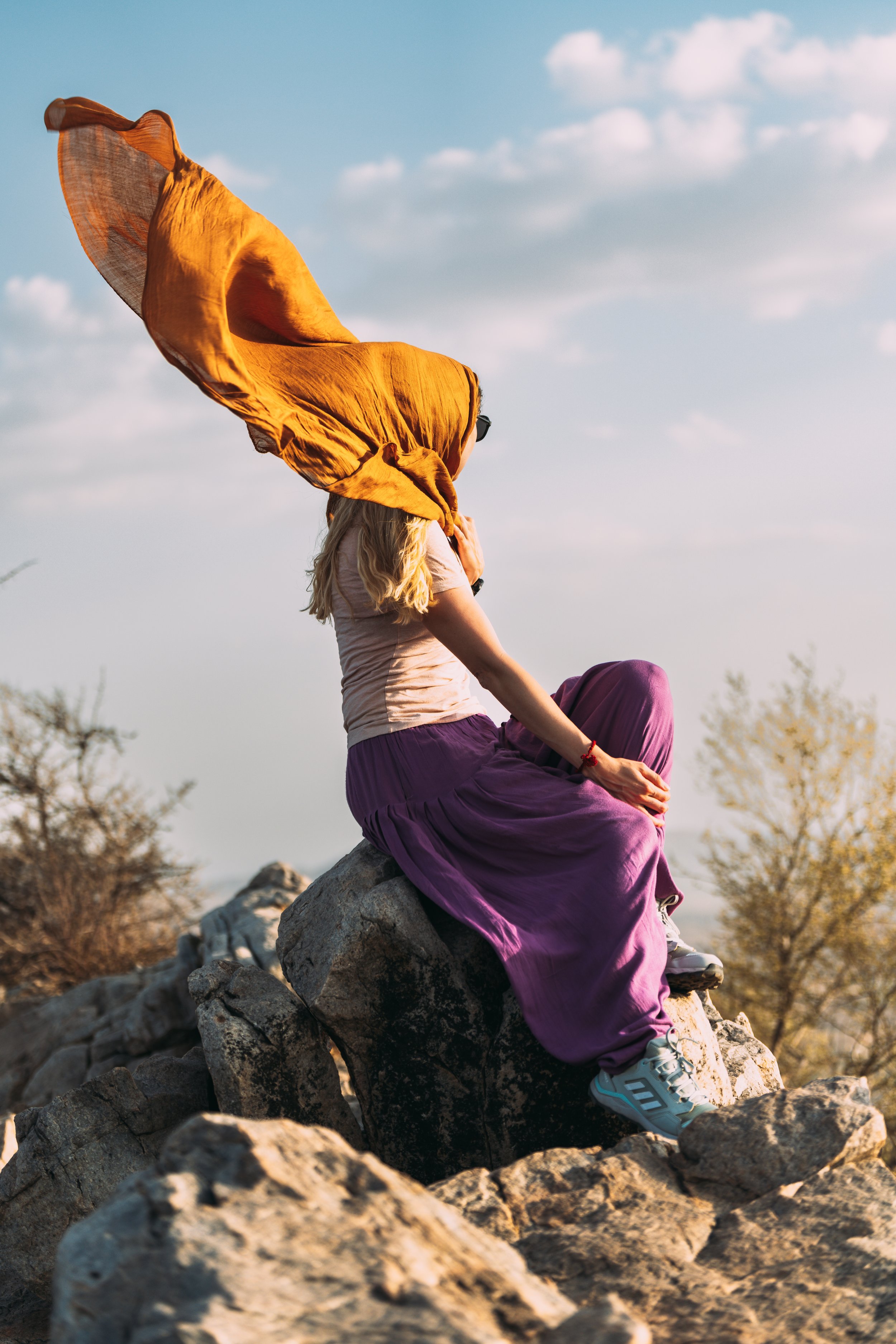 Voyageuse en tenue colorée assise sur un rocher face aux collines de Pushkar