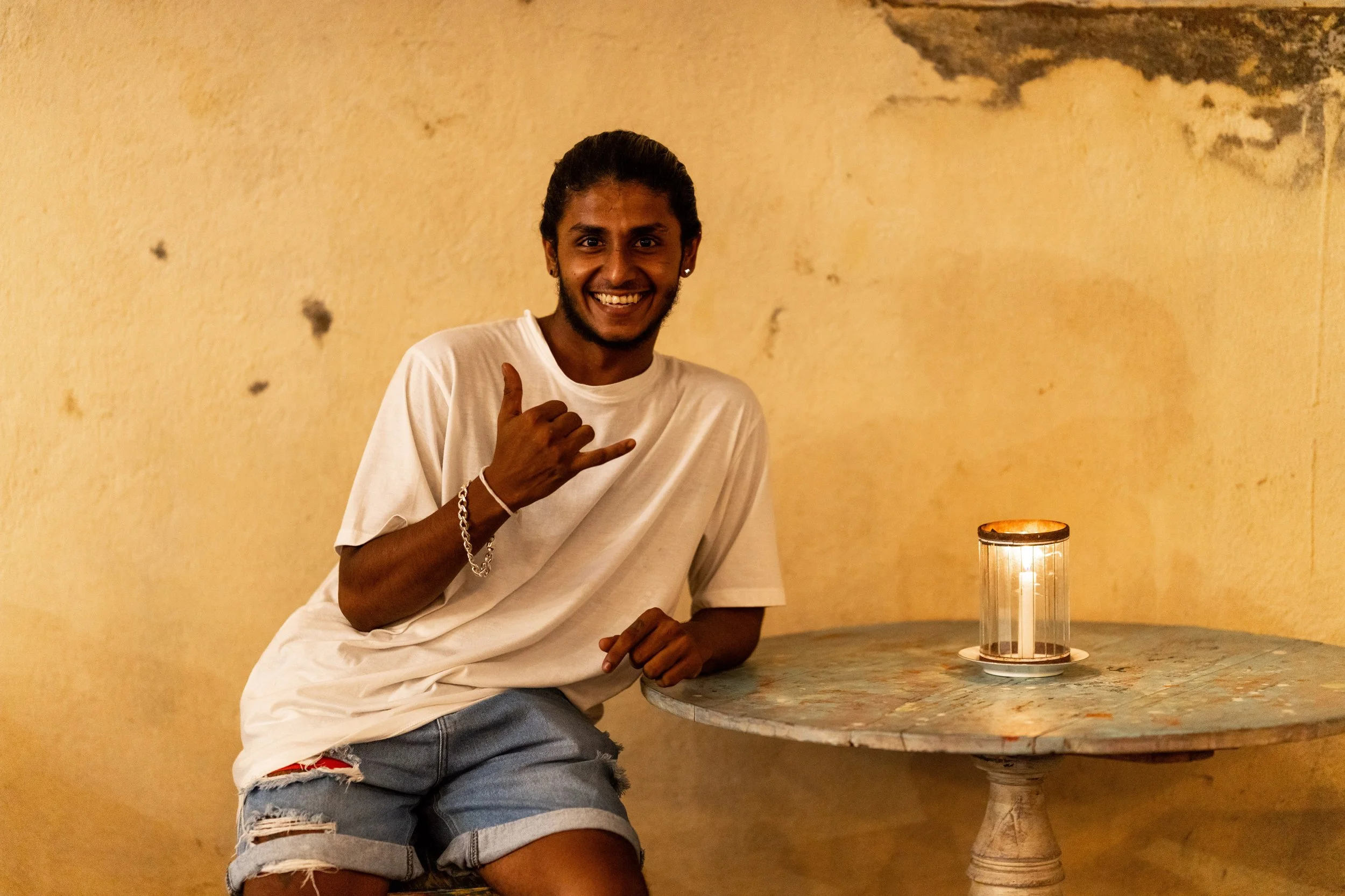 Sri-Lankais souriant accoudé à une table devant un mur ocre à Galle