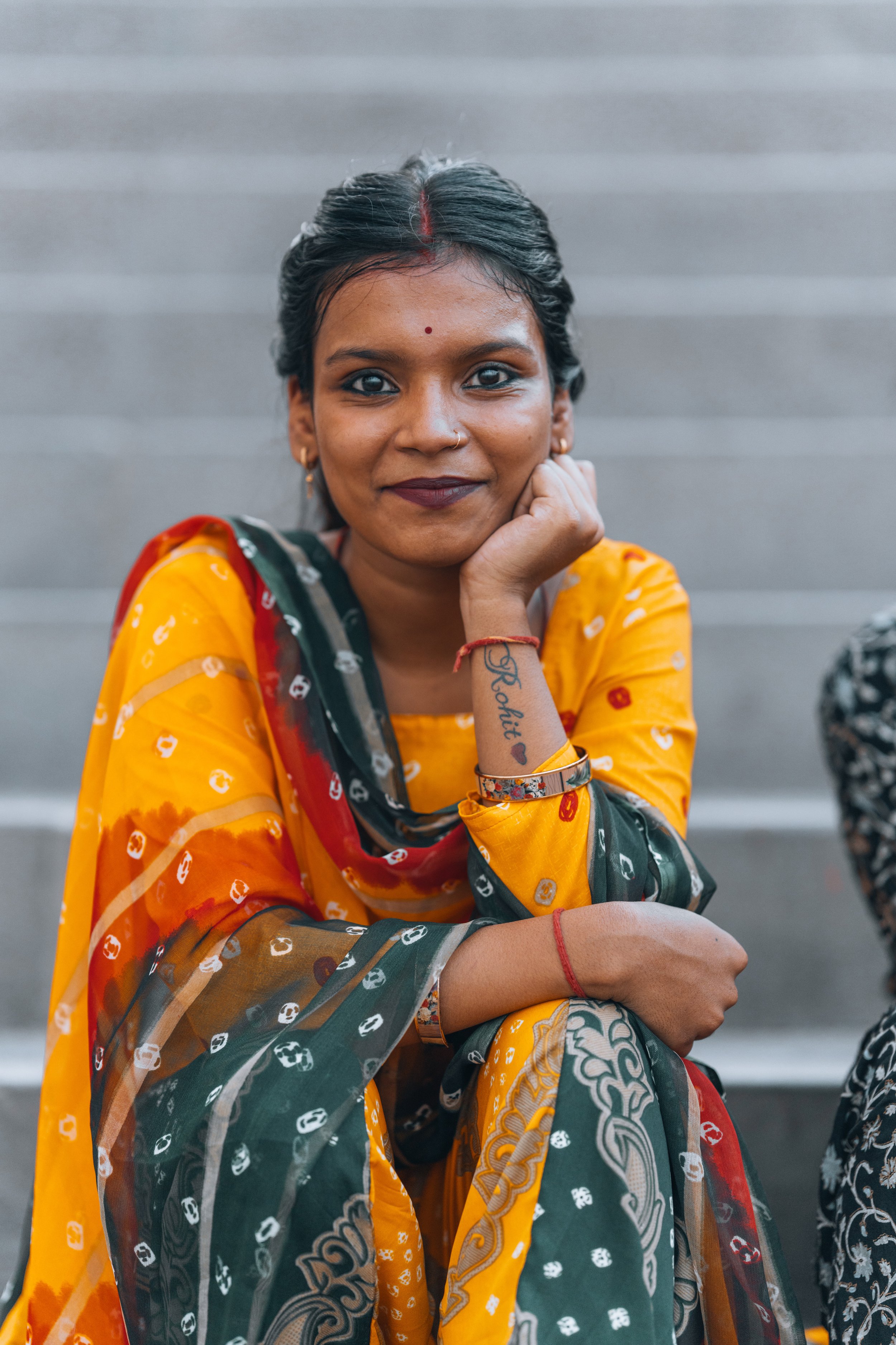 Jeune femme en sari orange assise sur les marches d'un ghat de Varanasi