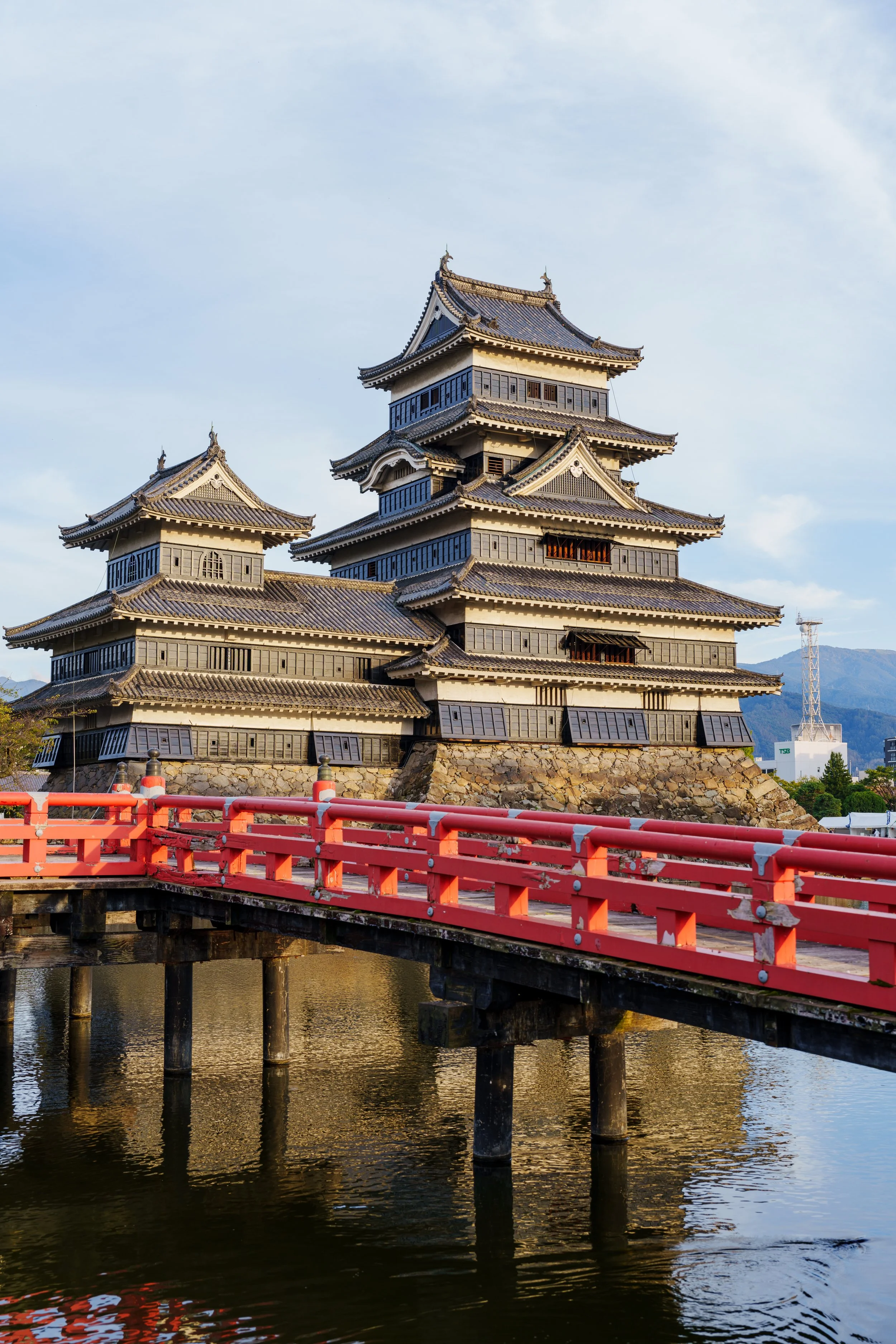 Château noir de Matsumoto et son pont rouge reflétés dans les douves