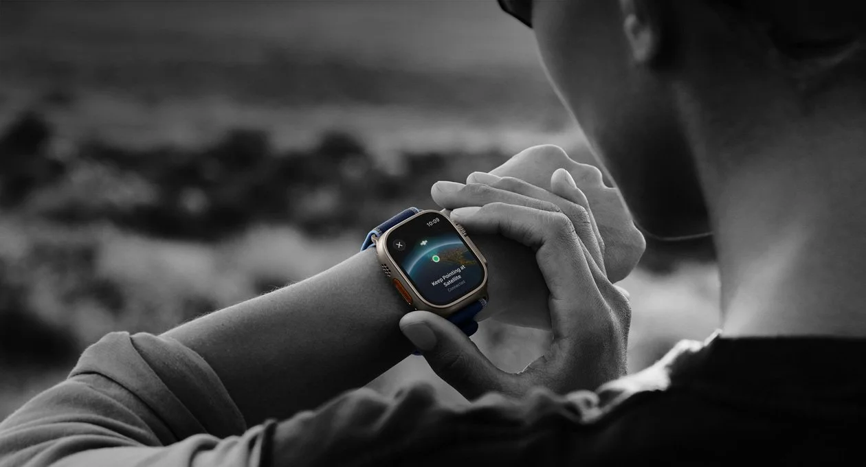 Main réglant une Apple Watch Ultra portée au poignet en noir et blanc