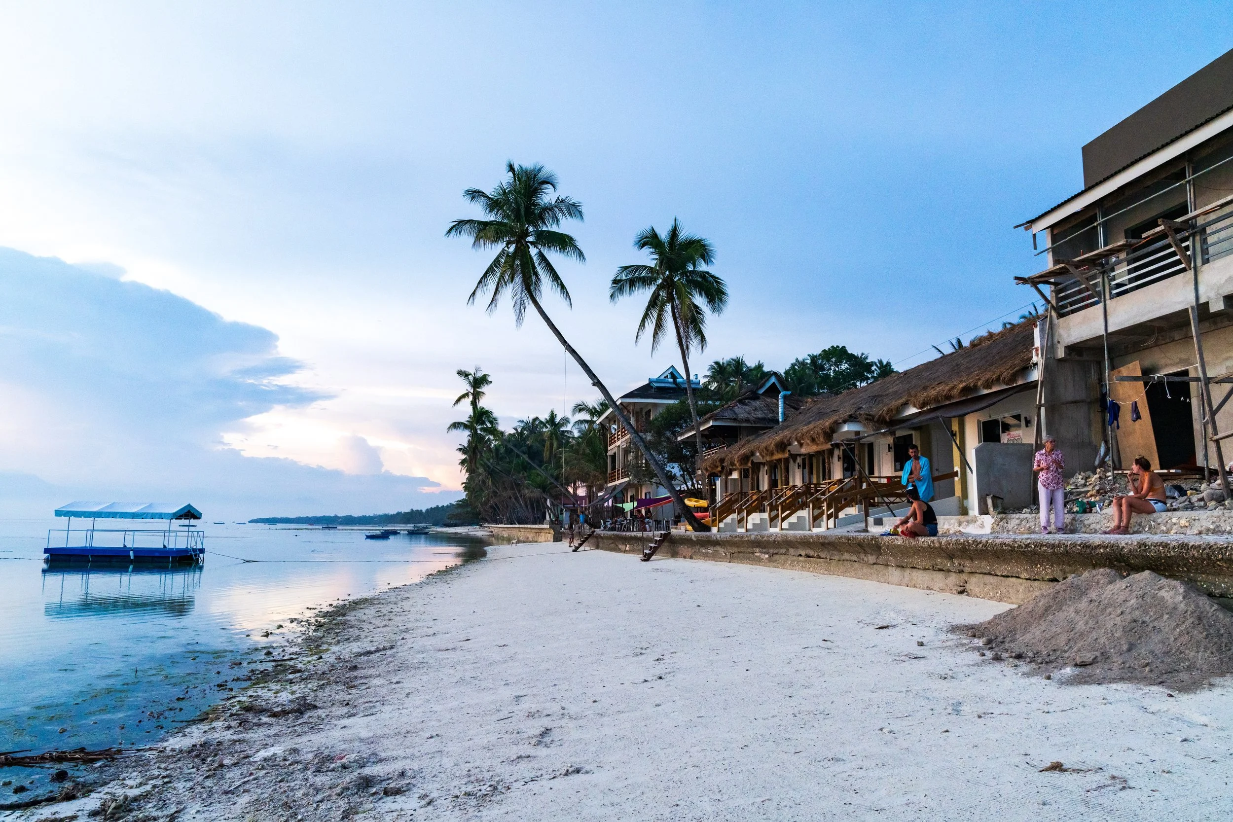 Plage de sable blanc bordée de cocotiers et de bungalows à San Juan sur Siquijor