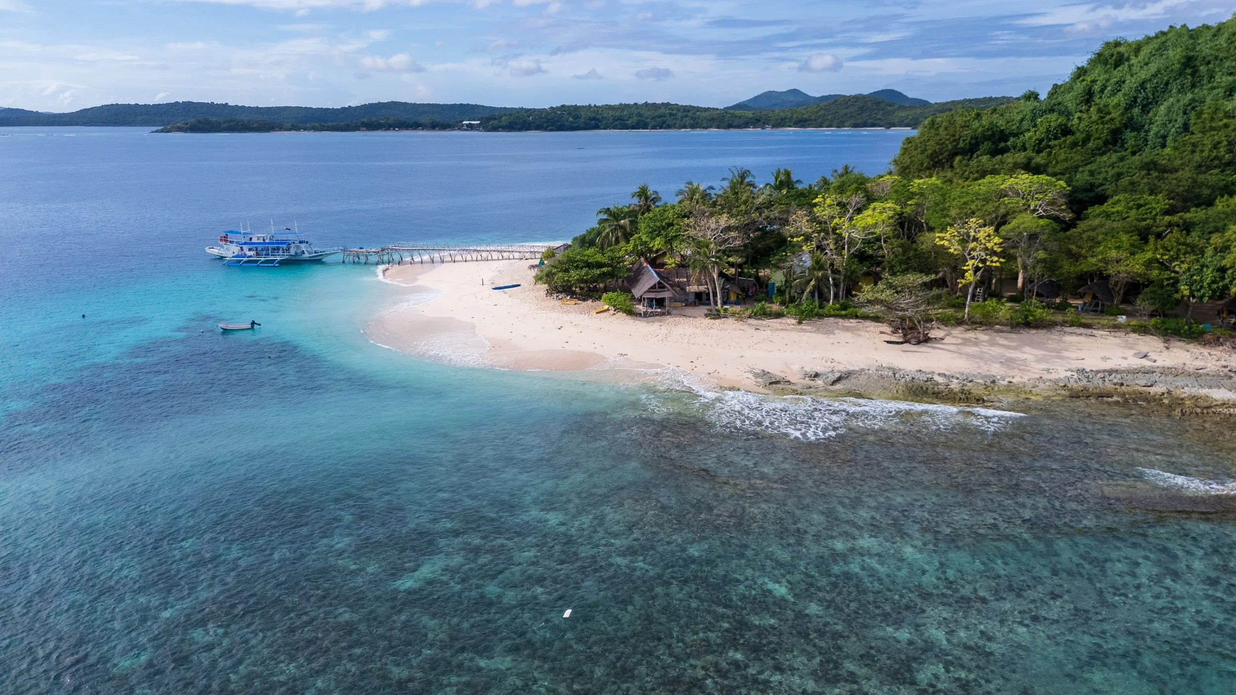 Camp de base sur une plage bordée de cocotiers et de coraux à Palawan