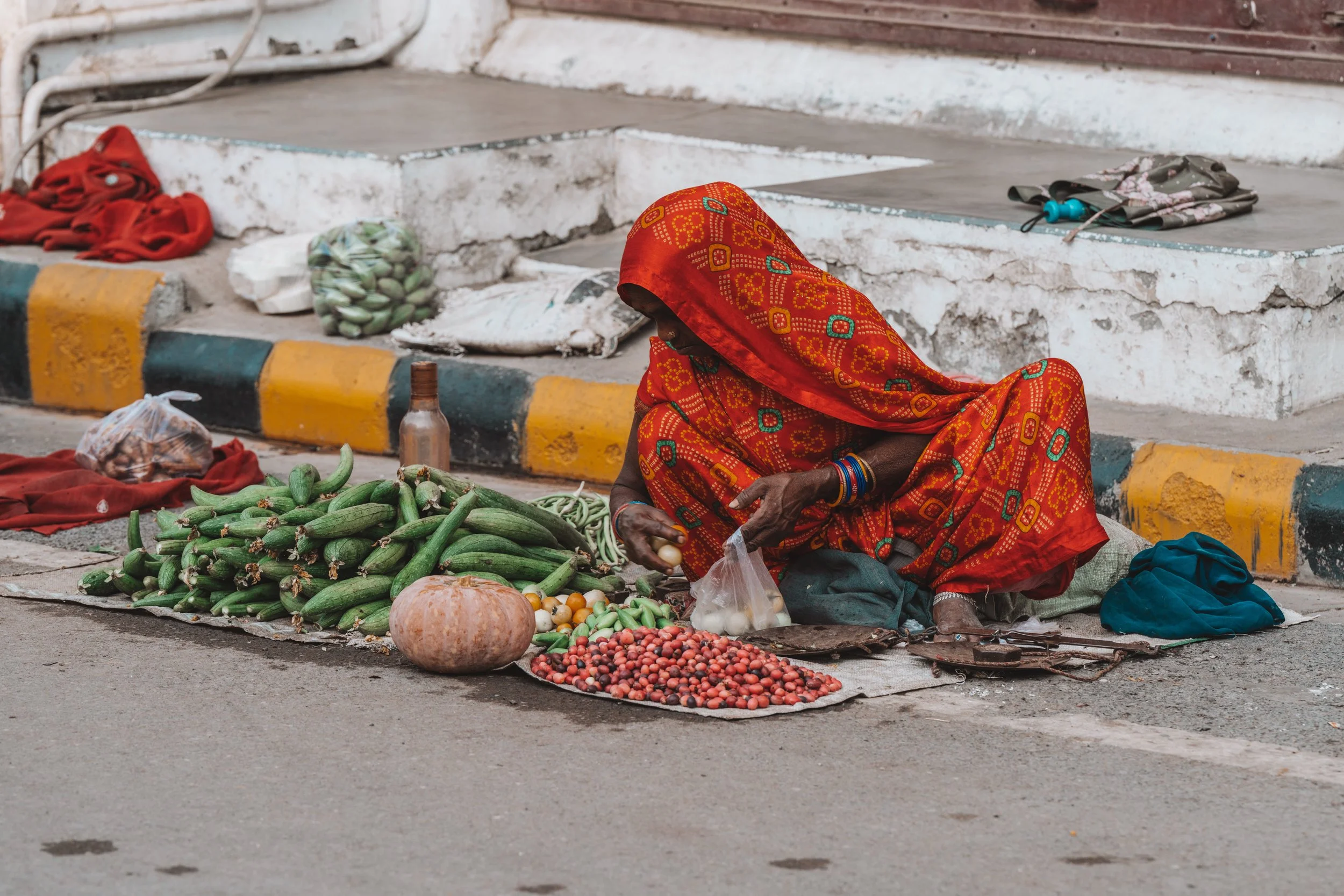 Vendeuse de légumes installée sur le trottoir dans une rue de Varanasi