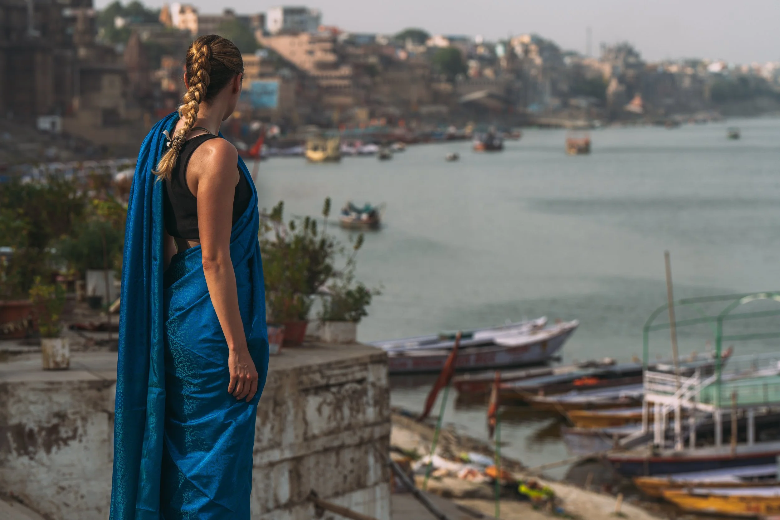 Voyageuse en sari bleu face au Gange et aux barques de Varanasi