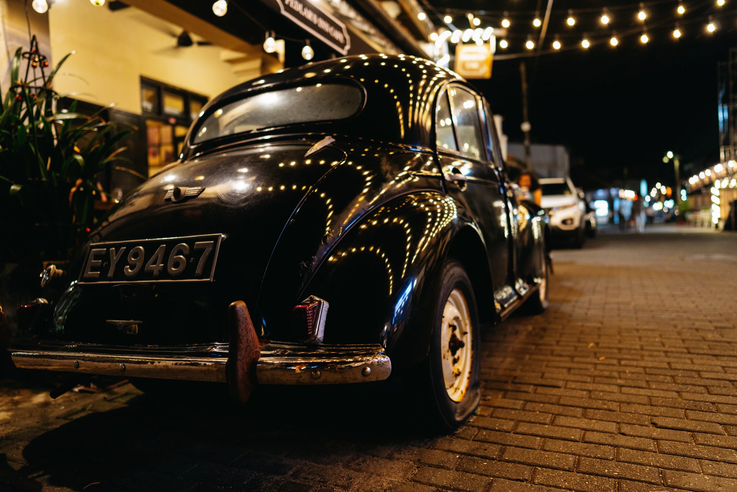 Voiture ancienne noire garée dans une rue illuminée du fort de Galle