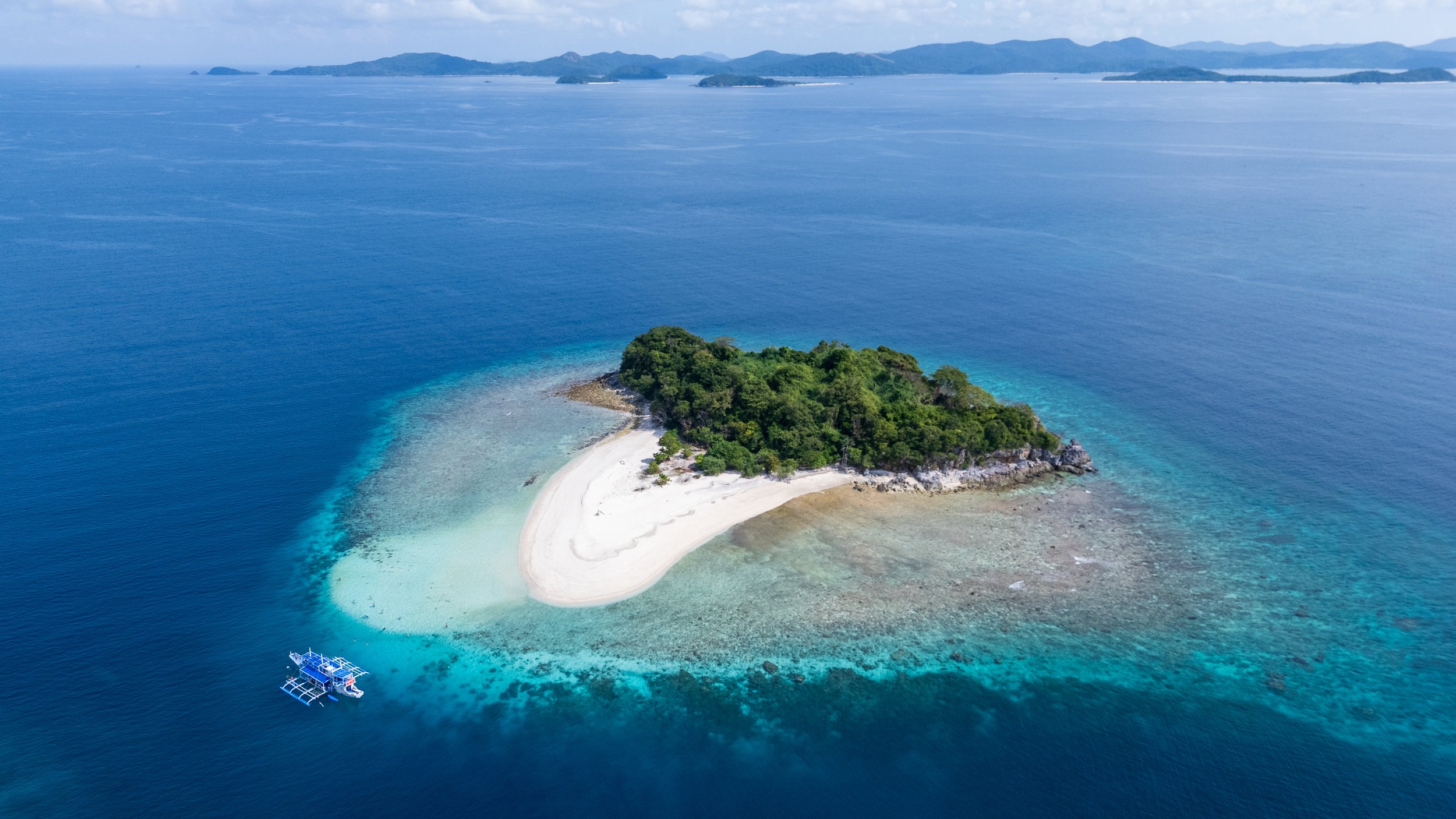 Vue aérienne d'un îlot désert entouré de récifs coralliens à Palawan