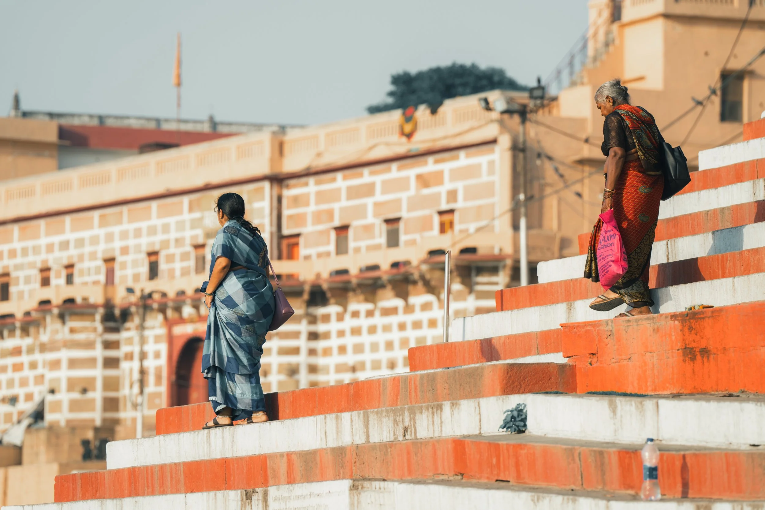 Femme en sari descendant les marches d'un ghat de Varanasi au bord du Gange