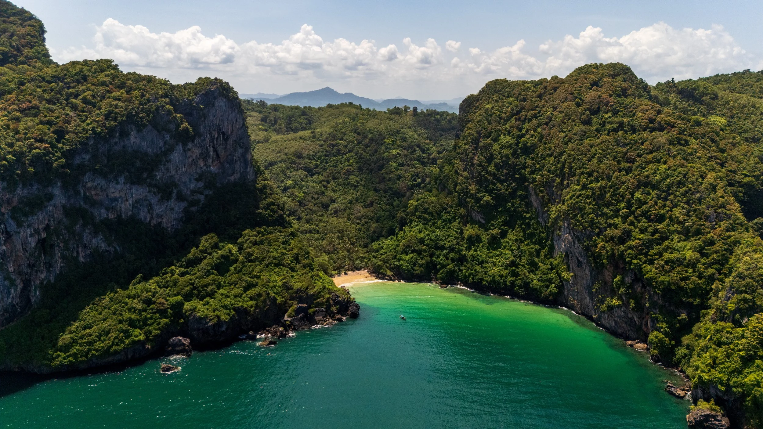 Crique turquoise bordée de falaises et de jungle sur l'île de Koh Mook