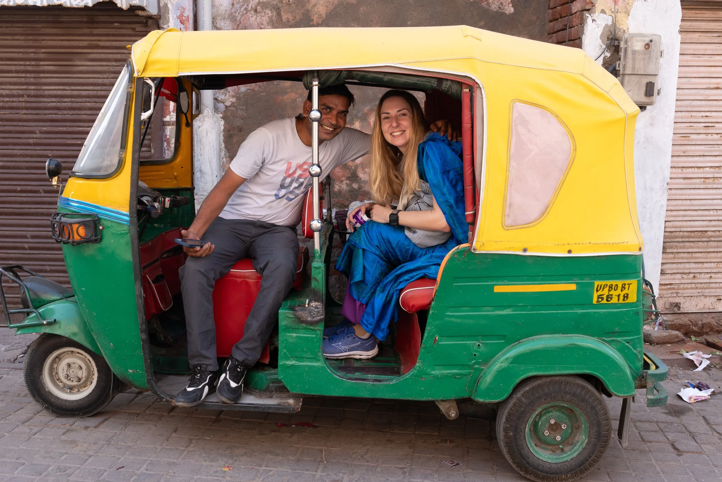 Voyageurs à bord d'un rickshaw vert et jaune dans les rues d'Agra