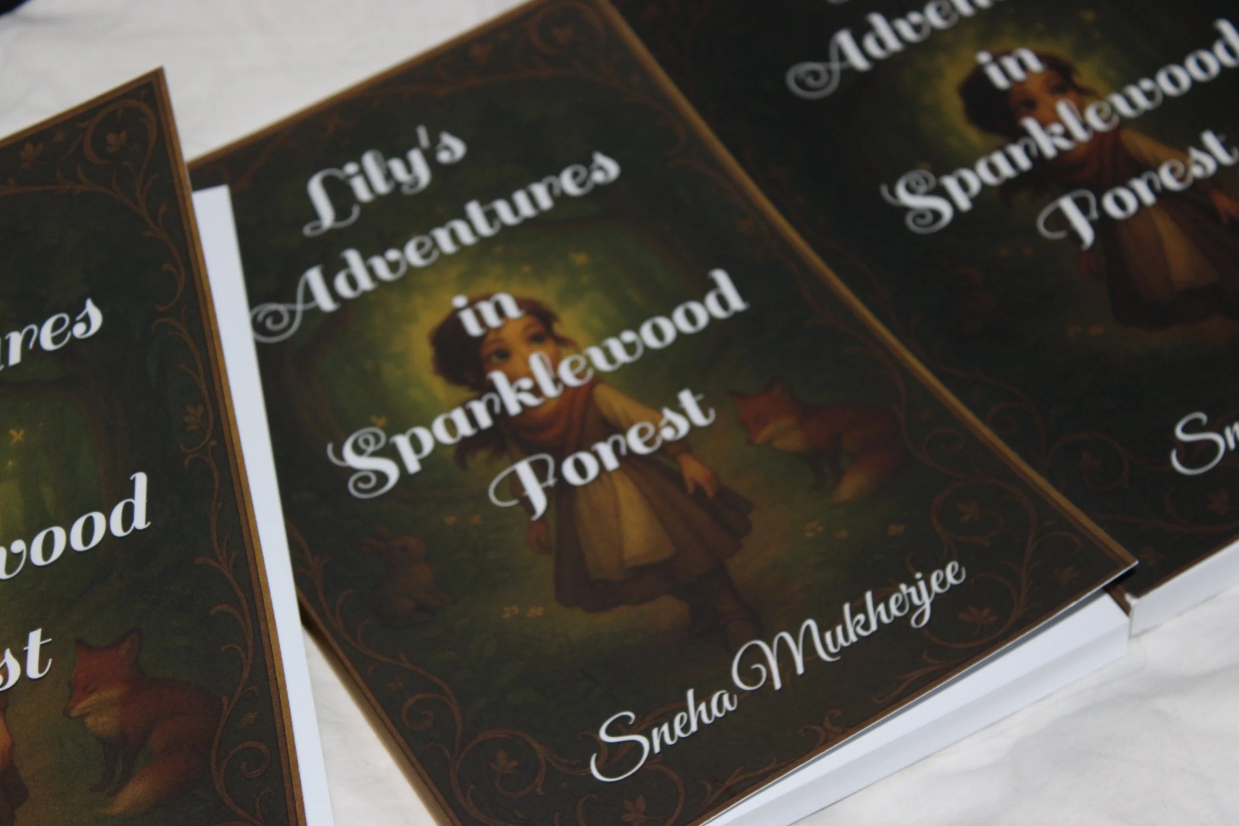 Book titled "Lily's Adventures in Sparklewood Forest" by Sneha Mukherjee, with a cover illustration of a young girl in a forest with animals.