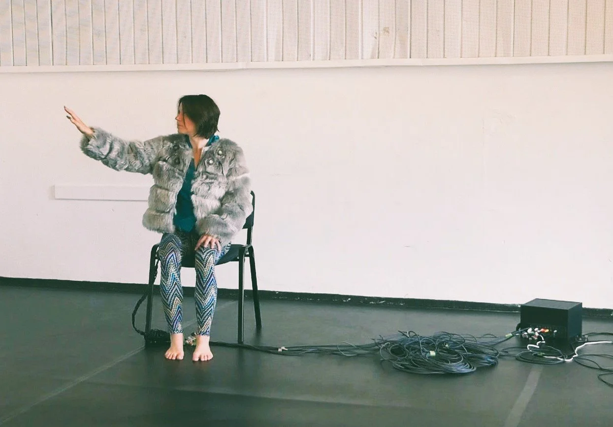 Marina Dessau seated during a tactile performance experiment exploring touch and perception.