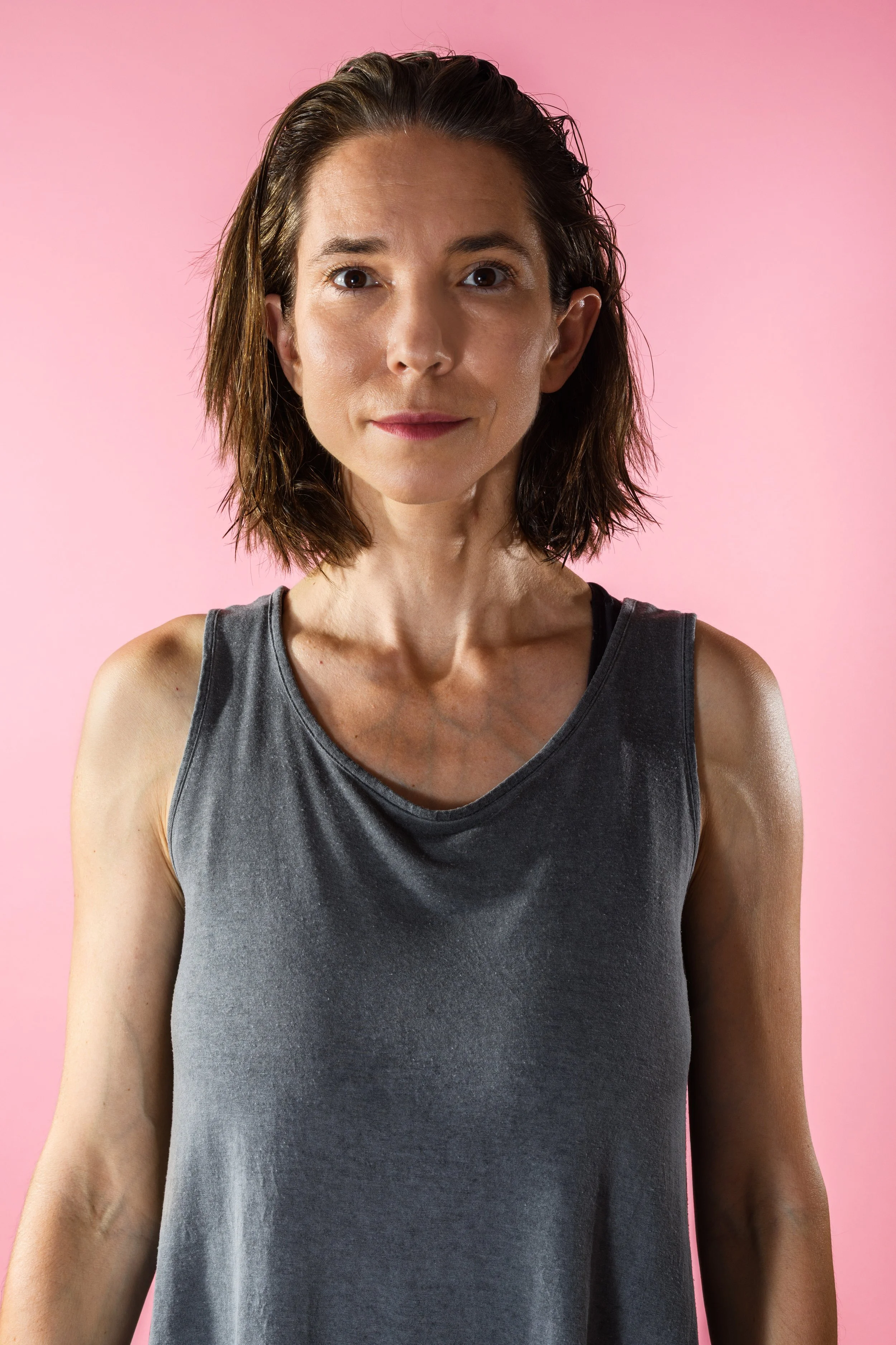 Portrait of performance artist Marina Dessau against a pink background.