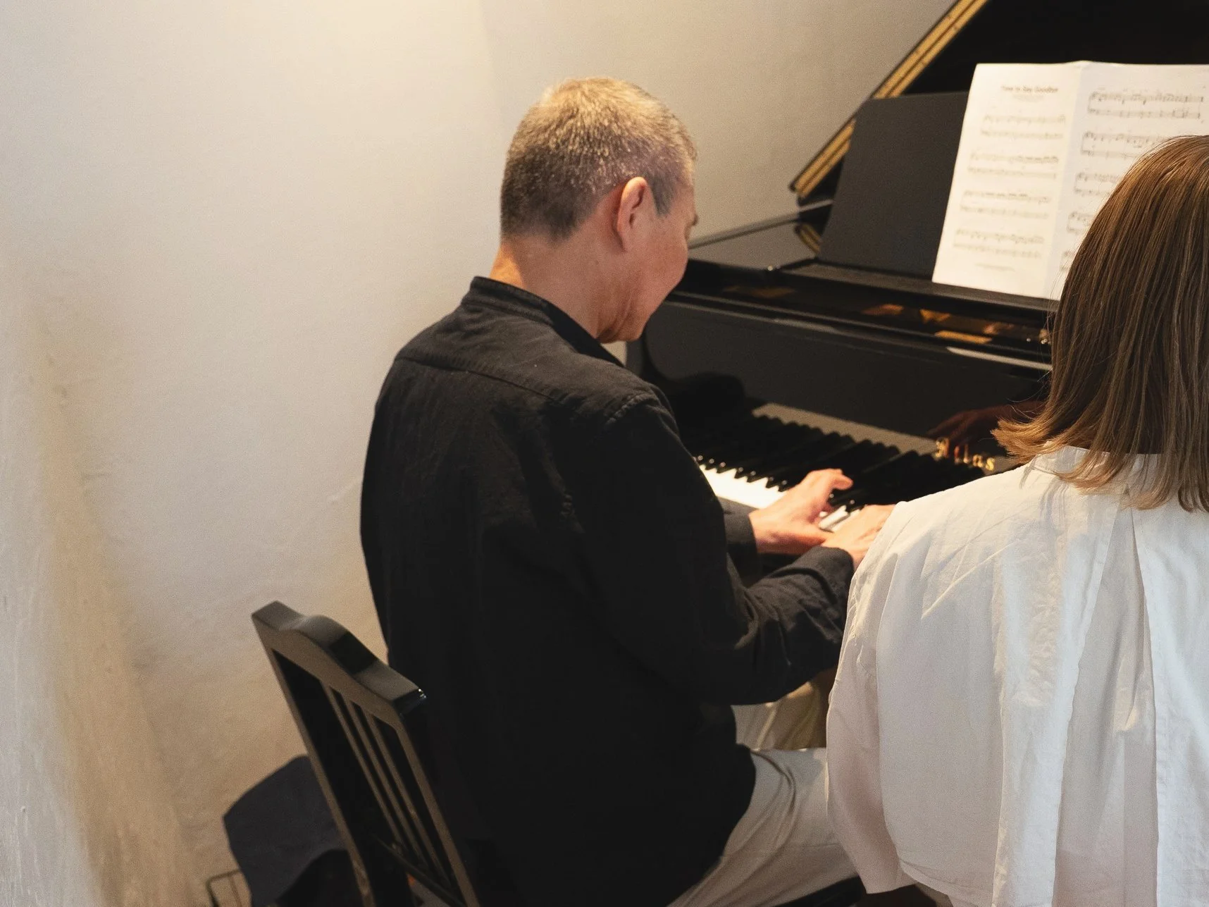 ピアノを弾いている男性と女性のグループの様子