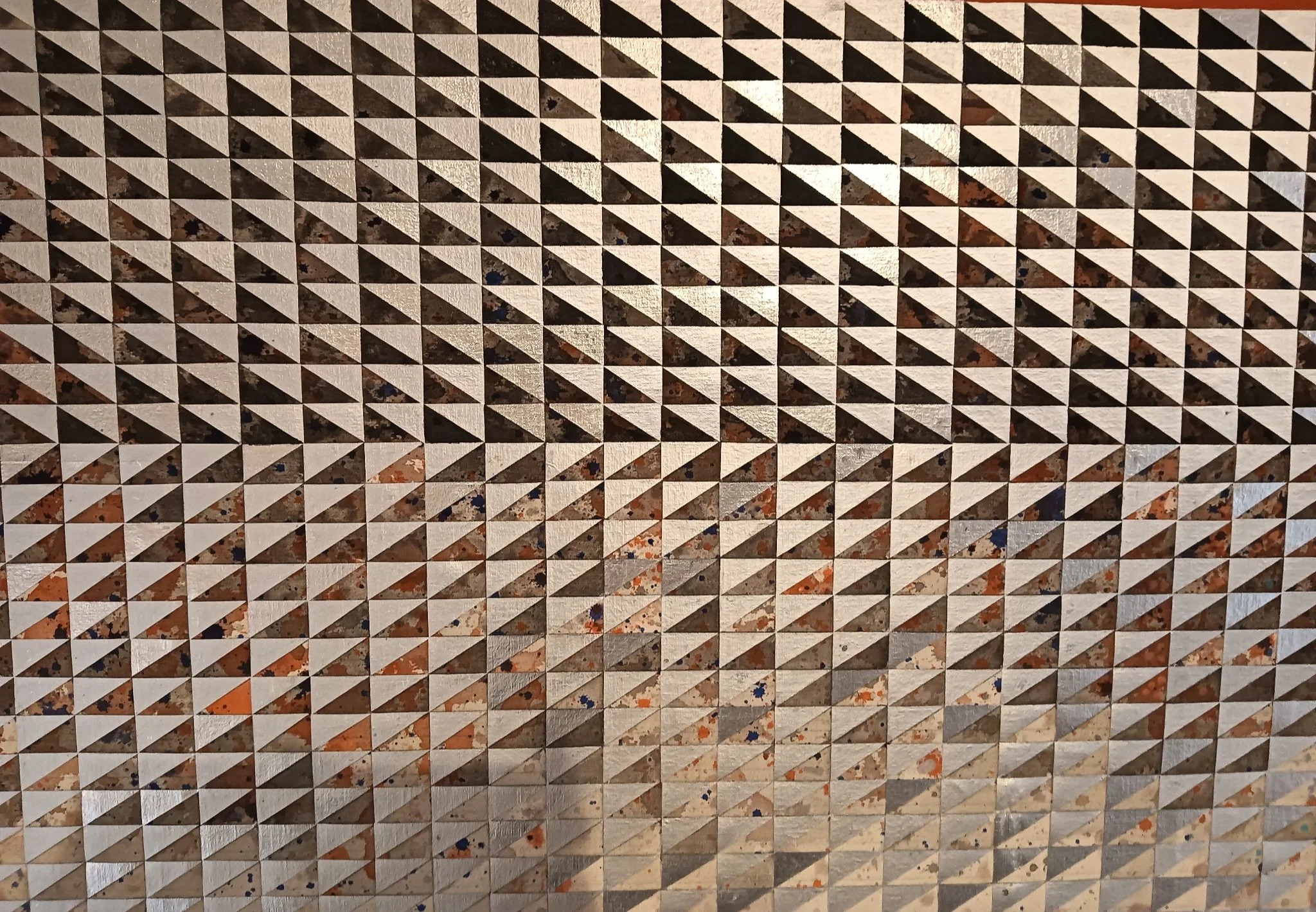 Close-up of a textured surface with a pattern of small triangles, featuring rust, dirt, and paint splatters.