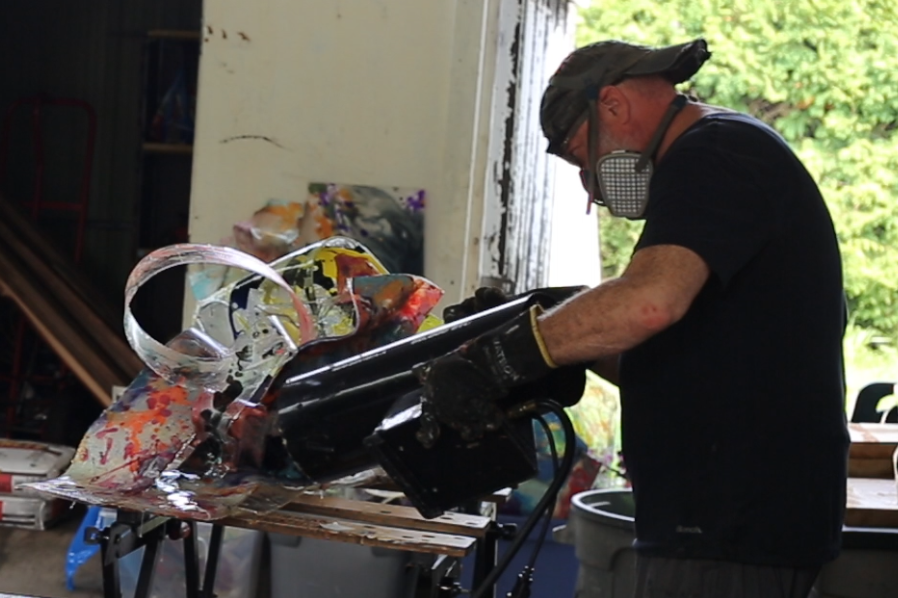 Mike Vandenberg, a Canadian contemporary artist, is working on a colorful, abstract sculpture in his outdoor studio.