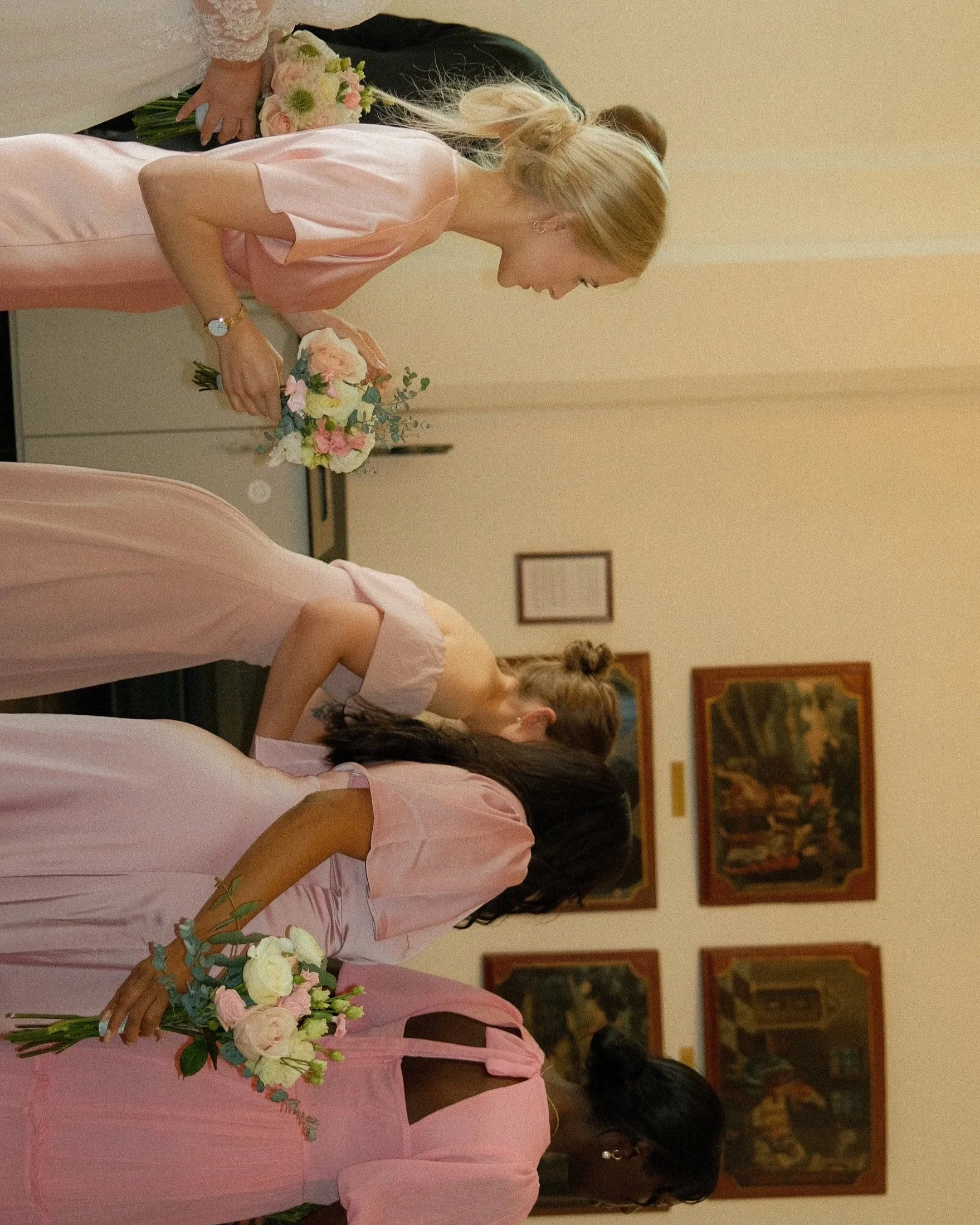 En gruppe mennesker med blomsterbuketter i en innendørs setting, sannsynligvis for en seremoni eller feiring.