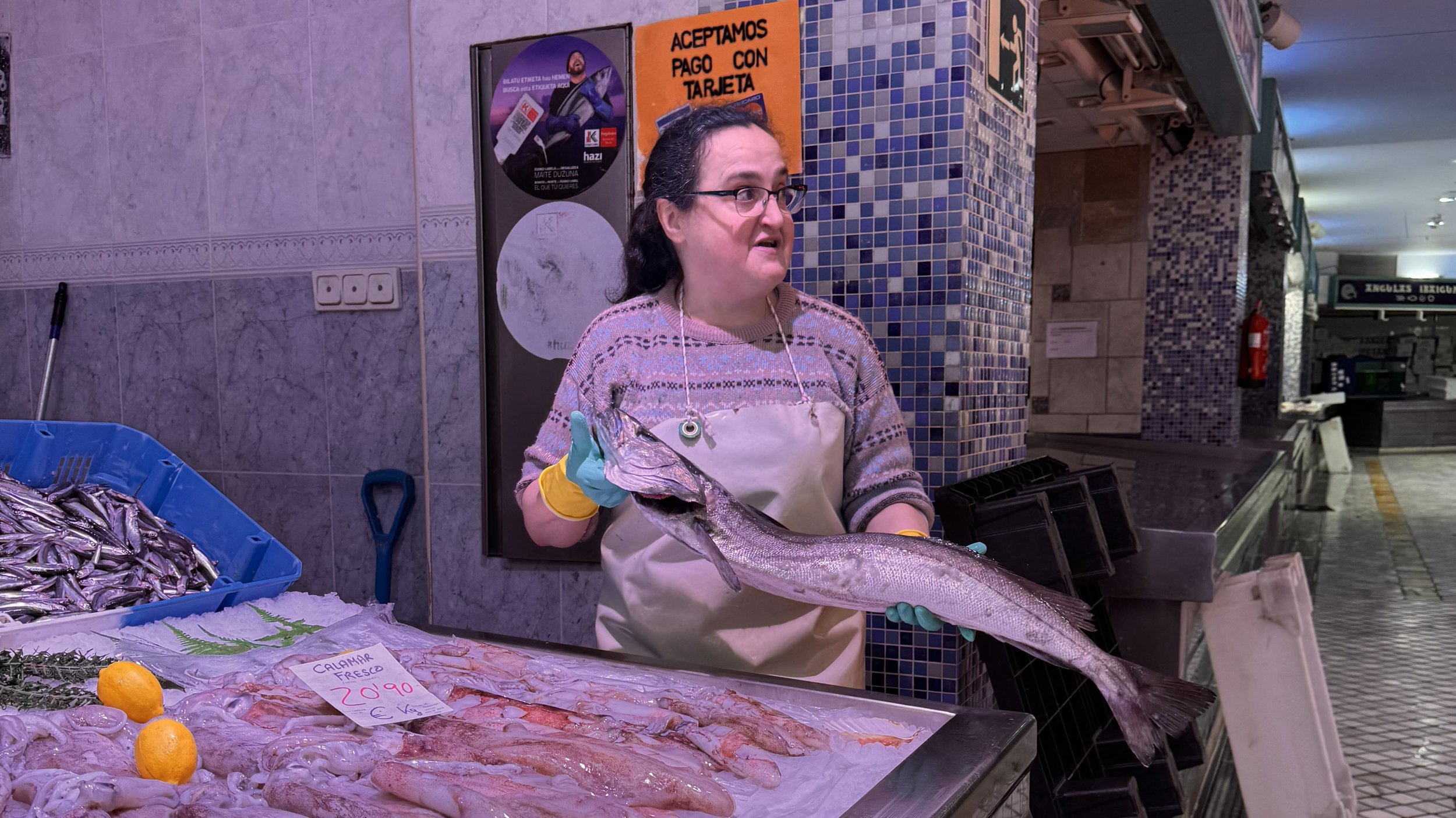 Fishmonger holding a large fish at a La Bretxa seafood market.