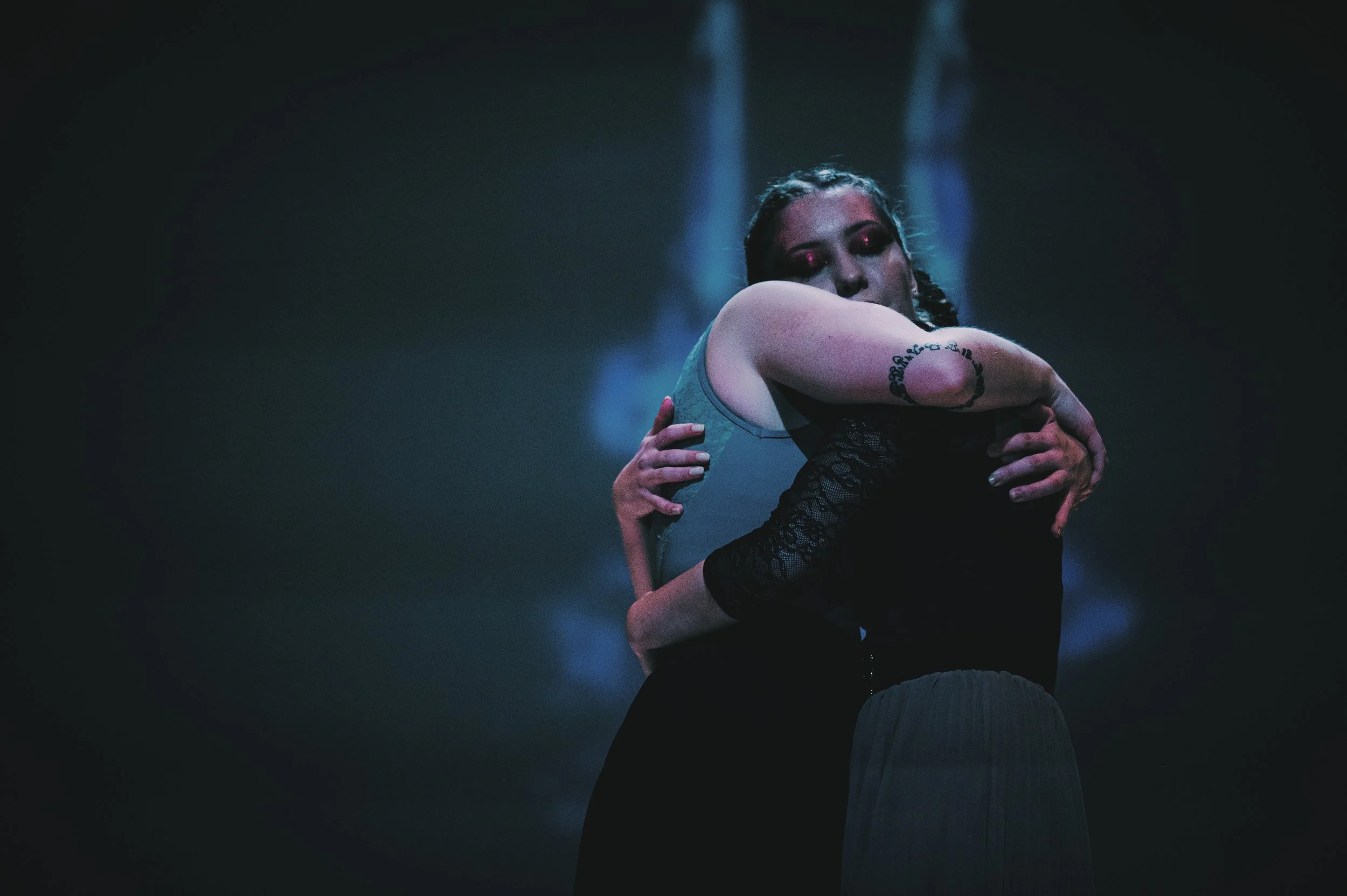 Two dancers share an embrace, holding tight to eachother.