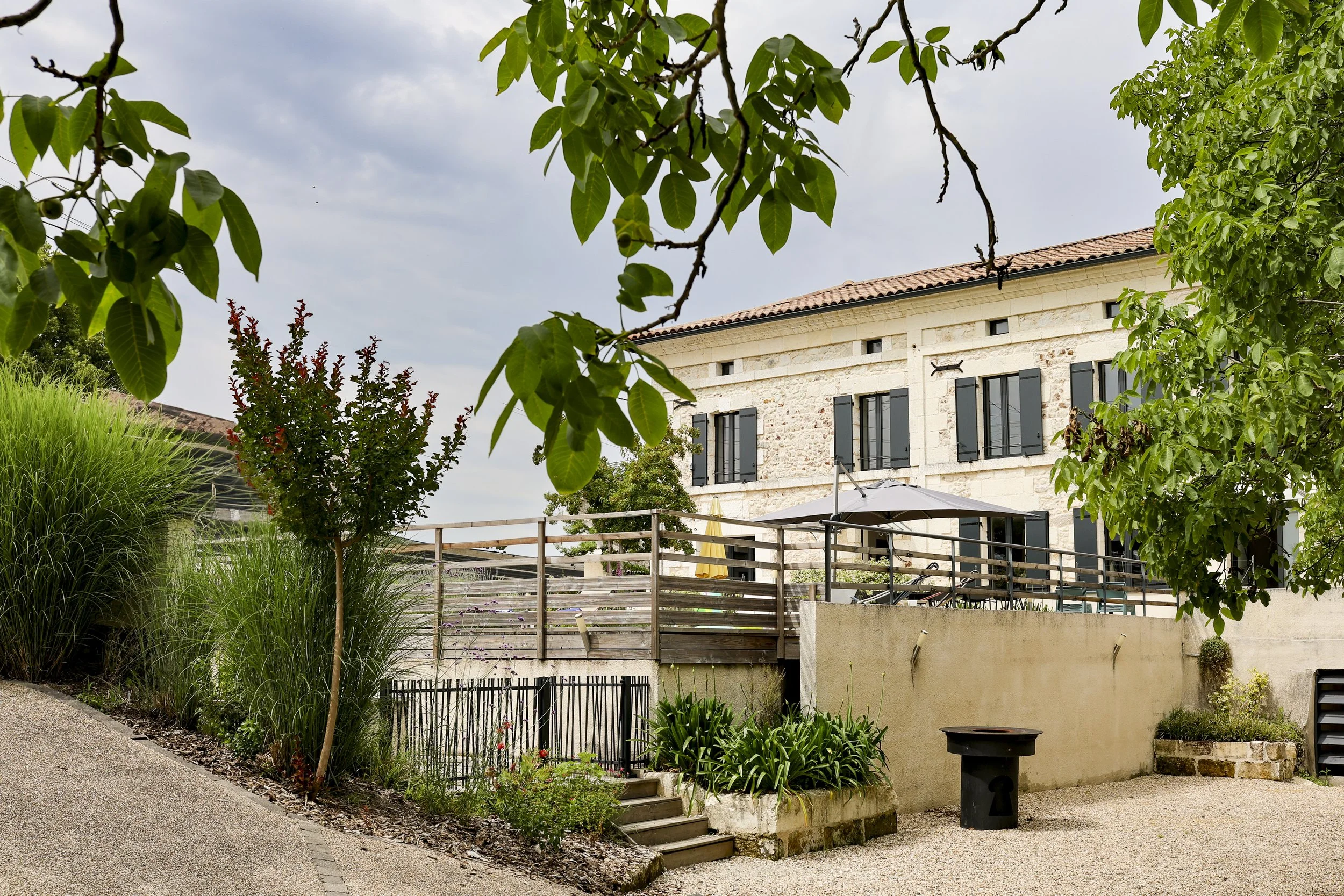 A white house with green shutters and a tile roof, and outdoor space. 