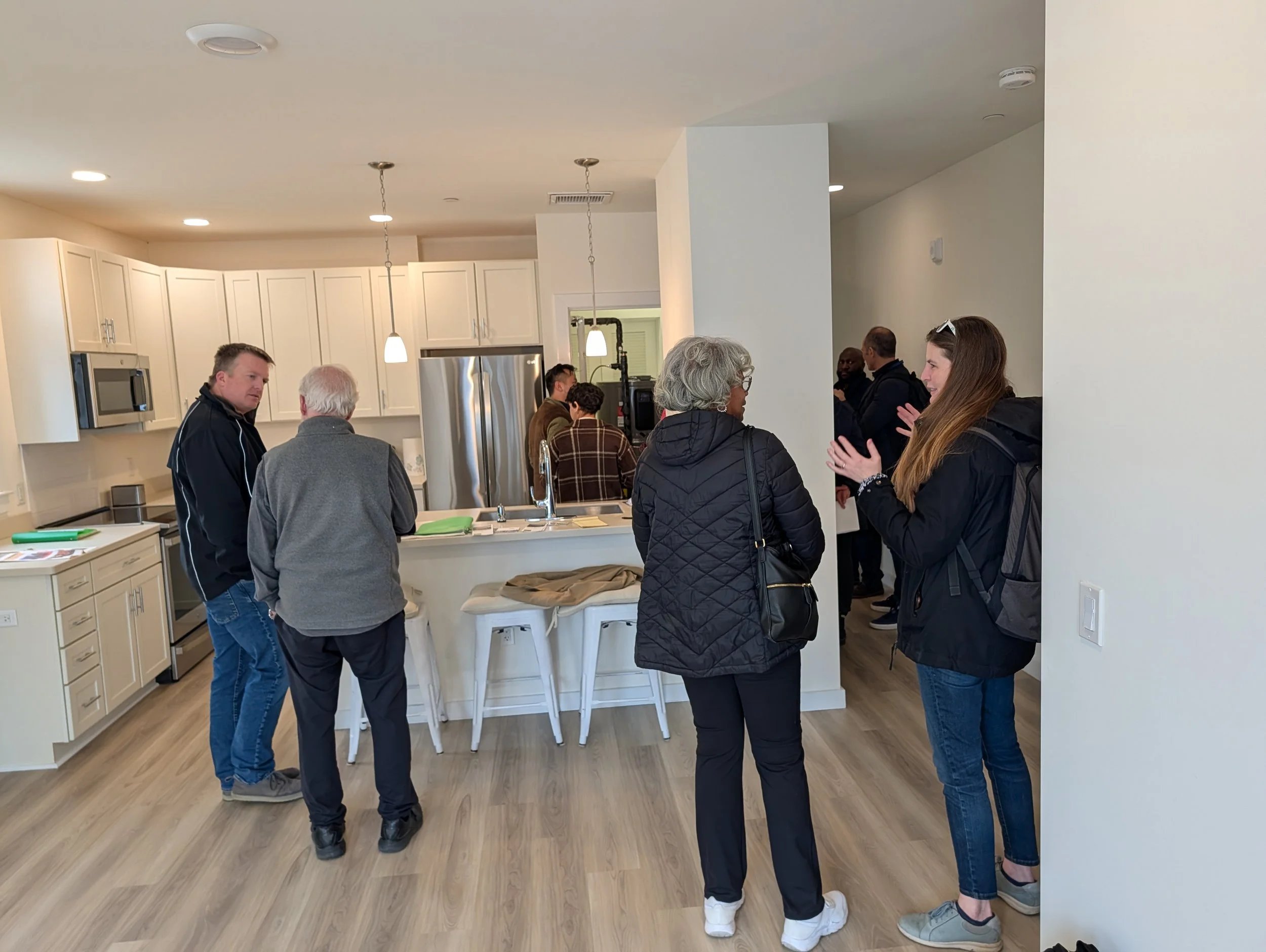 People stand in an empty unit during a walk-through of a modular home in Cambridge