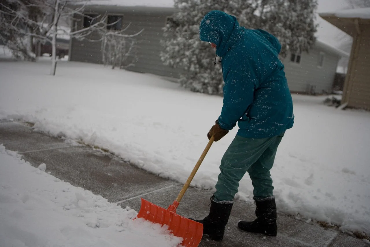 Person shoveling snow from a sidewalk