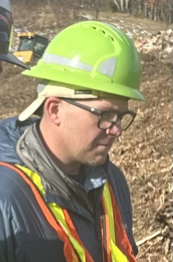 Construction worker with green hard hat and reflective vest on site