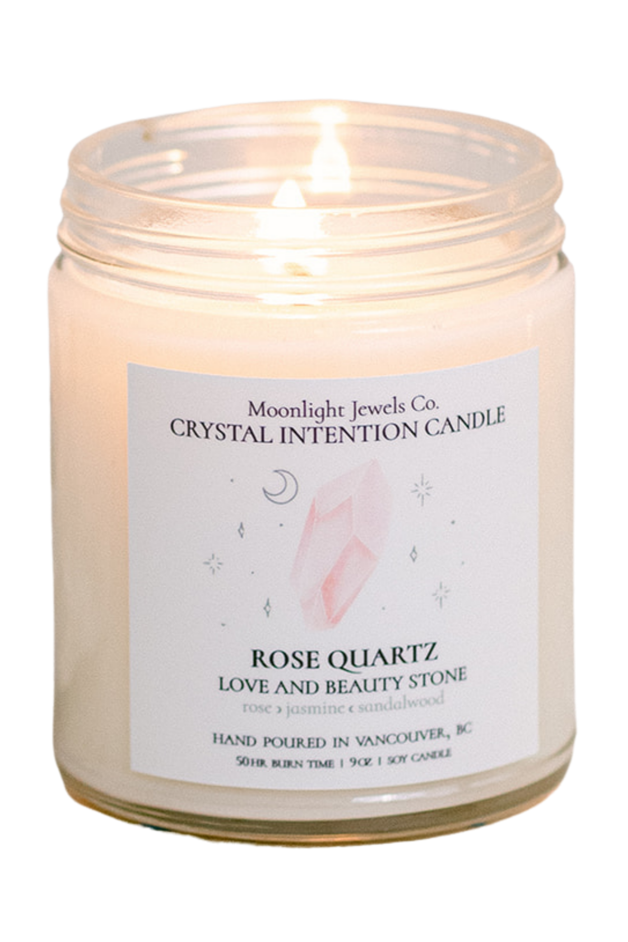 A lit candle in a glass jar labeled 'Moonlight Jewels Co. Crystal Intention Candle' with a rose quartz stone illustration, surrounded by small celestial symbols on the label.