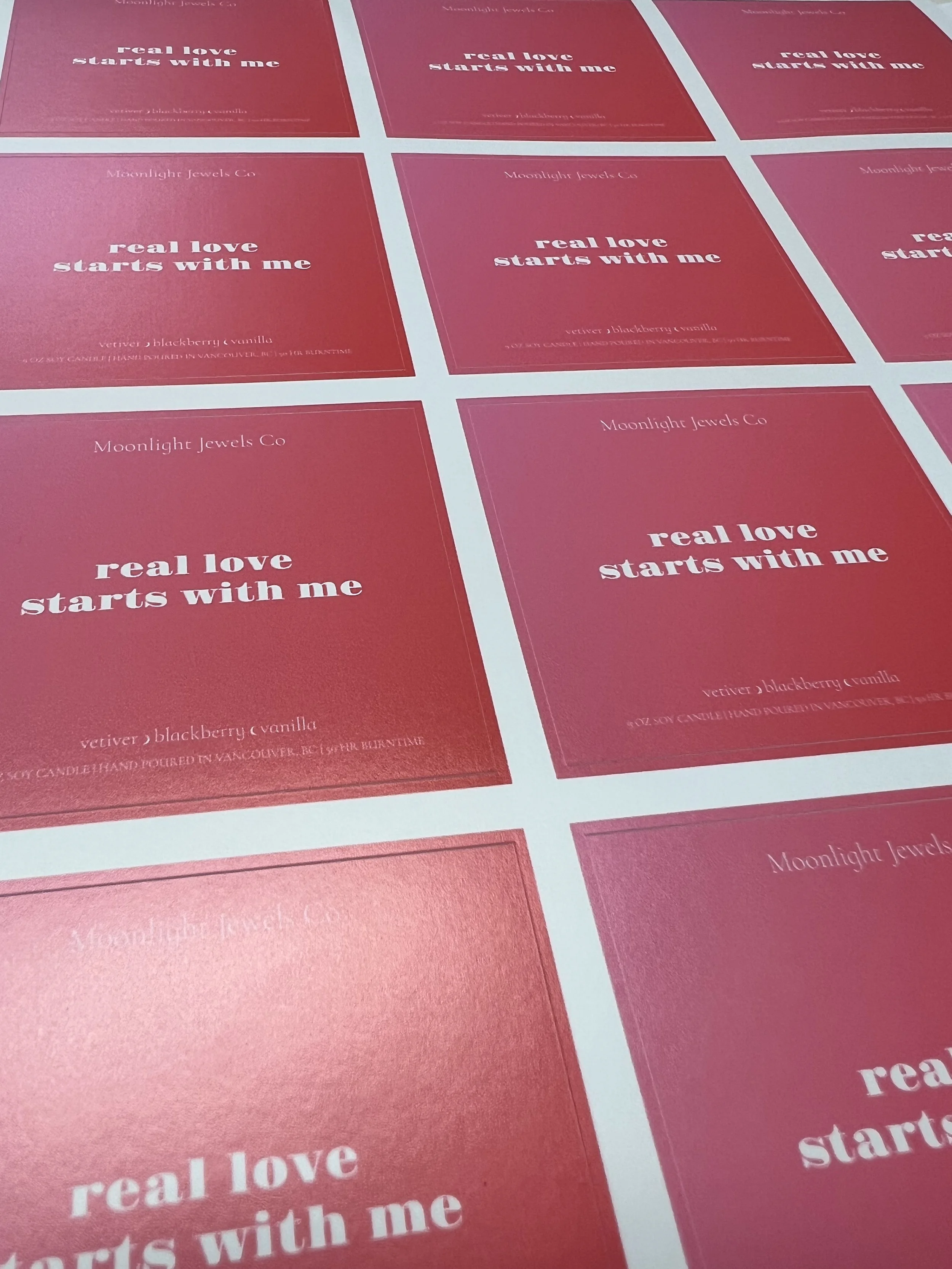 Multiple red cards with white text promoting Midnight Jewels Co. products, each stating 'real love starts with me' and mentioning blackberry vanilla scent and hand poured candles in Vancouver.