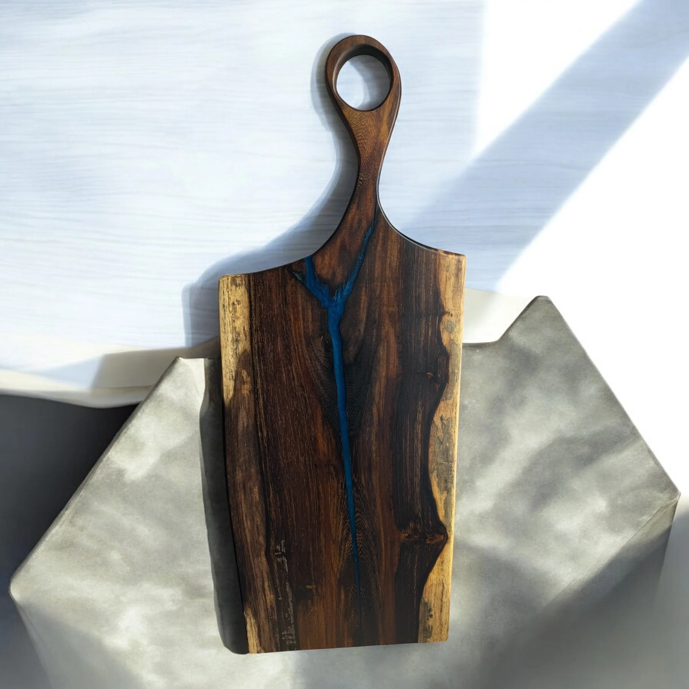 Wooden cutting board with blue resin inlay on geometric gray background