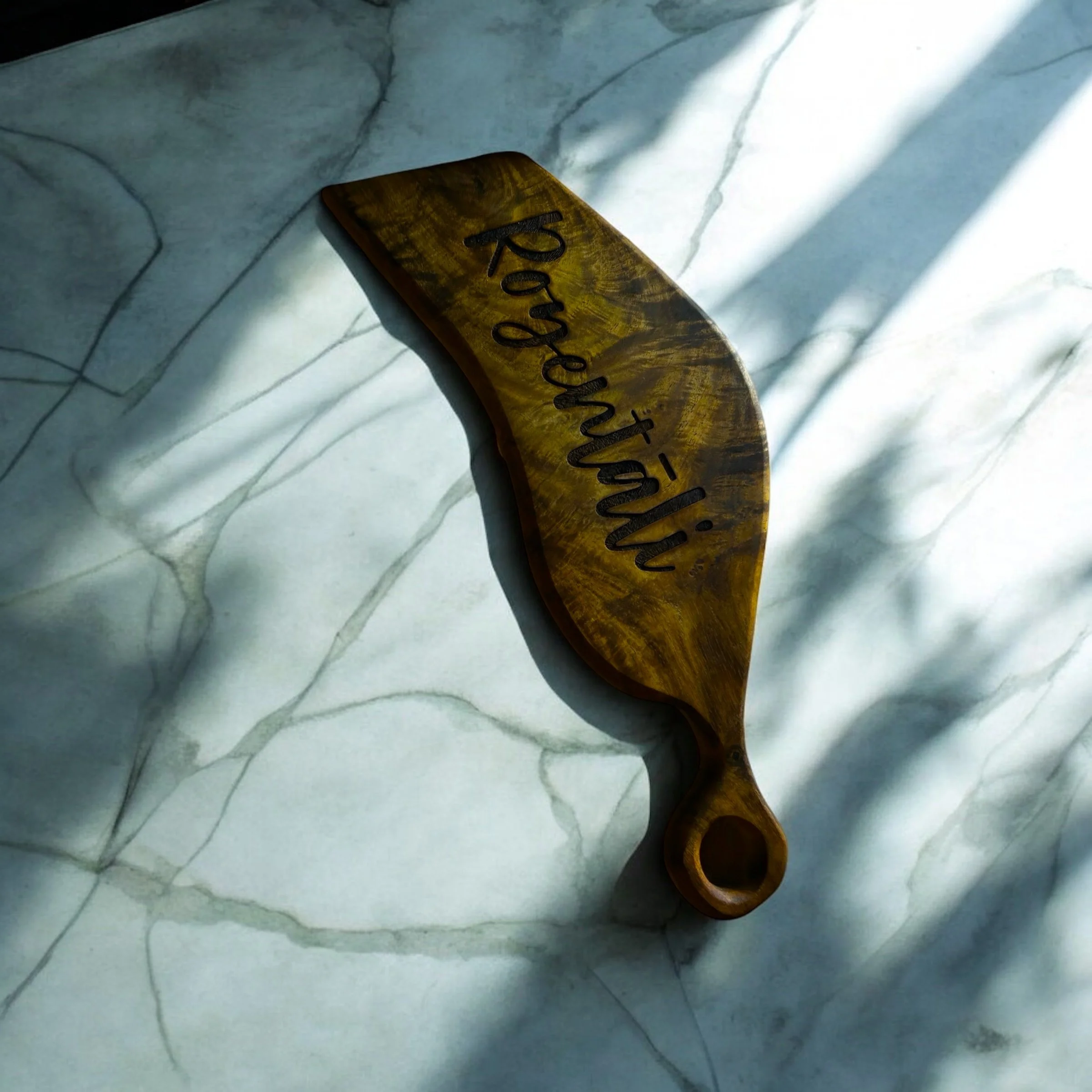 Wooden board with "Rozentāli" engraved, placed on a marble surface