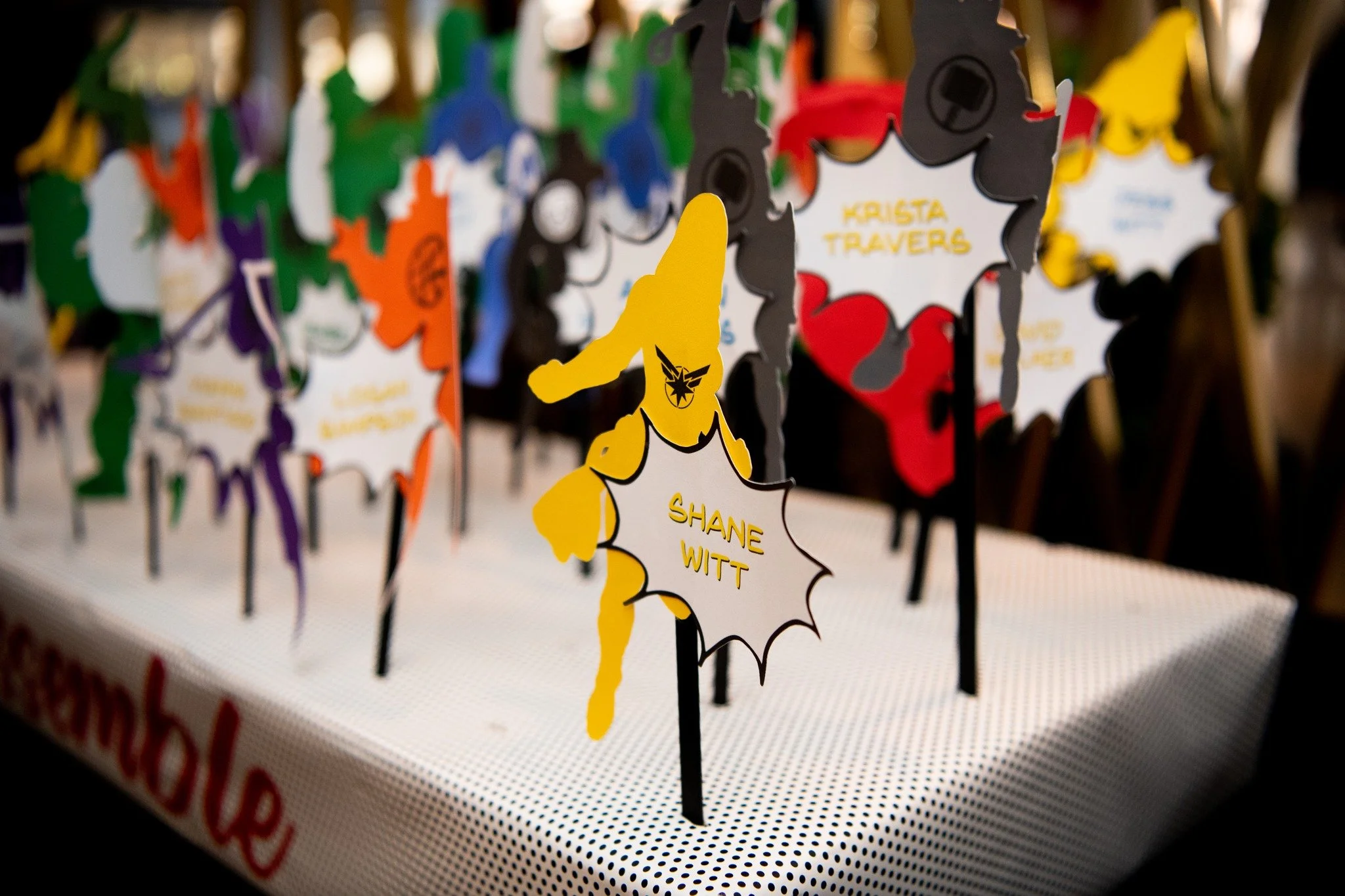 Colorful paper cutouts with each name written on them, displayed on sticks for a celebration or event, including names like Shane Witt and Krista Travers.