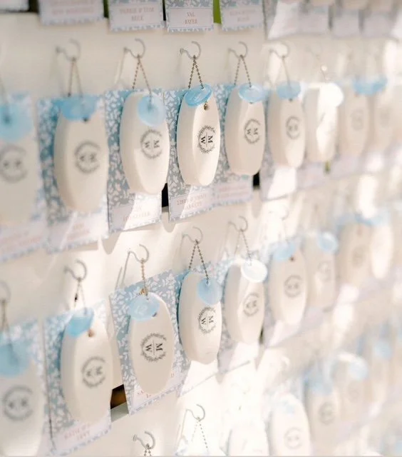 Display of multiple small white pouches with blue decorative accents hanging on hooks, arranged in rows.