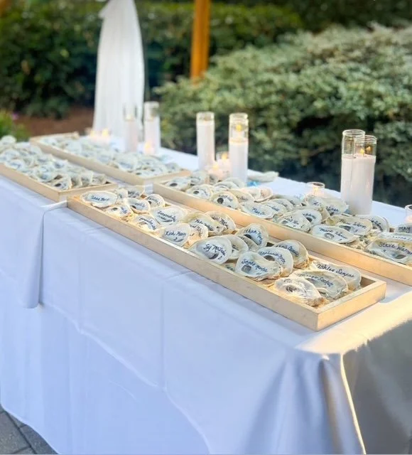 Table with personalized cookies in boxes, candles, and a white umbrella in an outdoor setting.