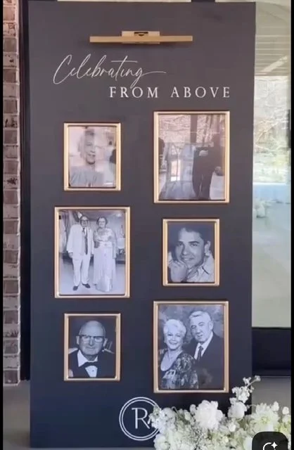 A black photo display board with the words "Celebrating FROM ABOVE" at the top, six framed black-and-white photographs of people, and a bouquet of white flowers at the bottom.