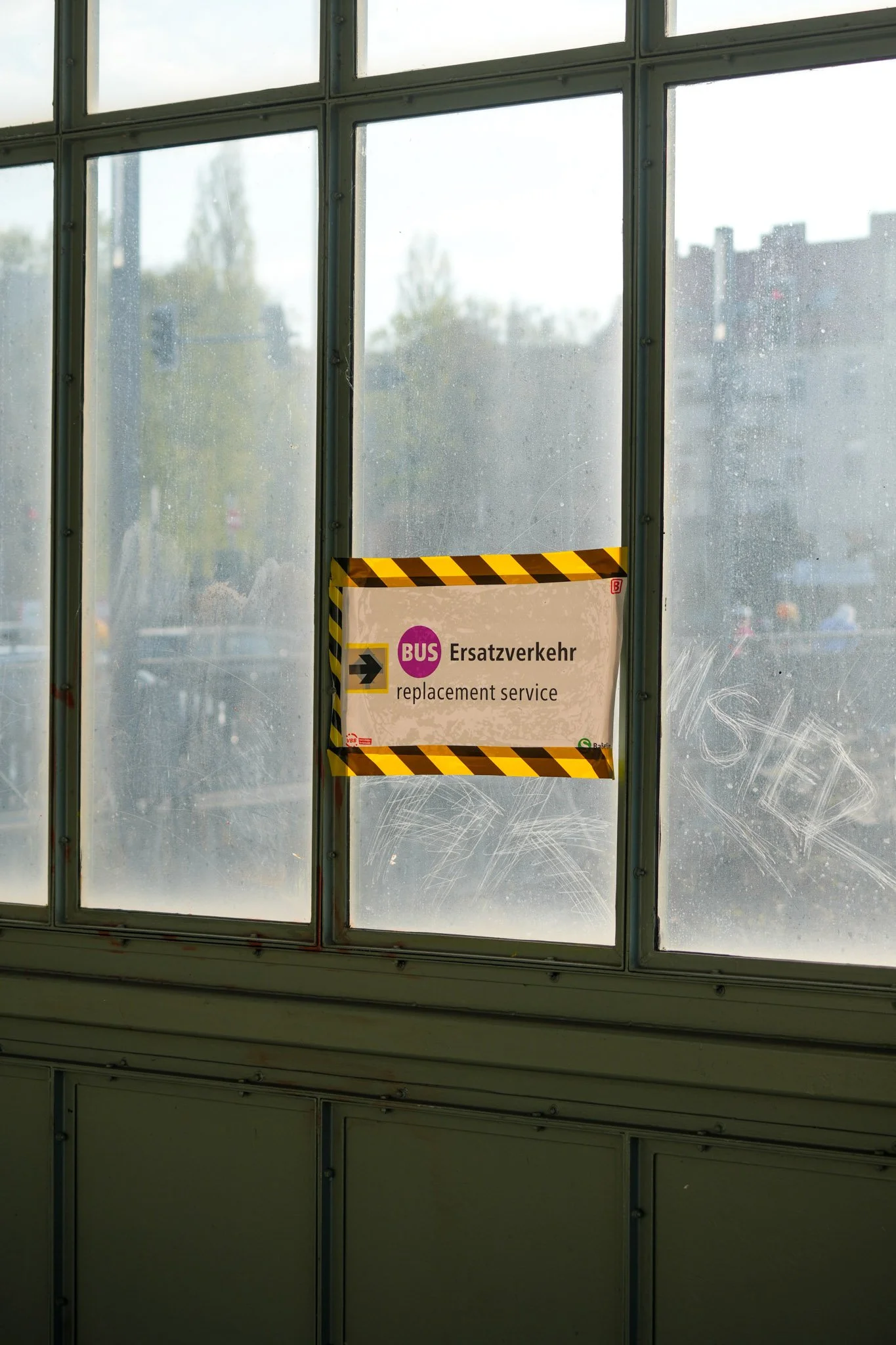 Schild für Bus-Ersatzverkehr an einem Fenster mit gelb-schwarz gestreiftem Band.