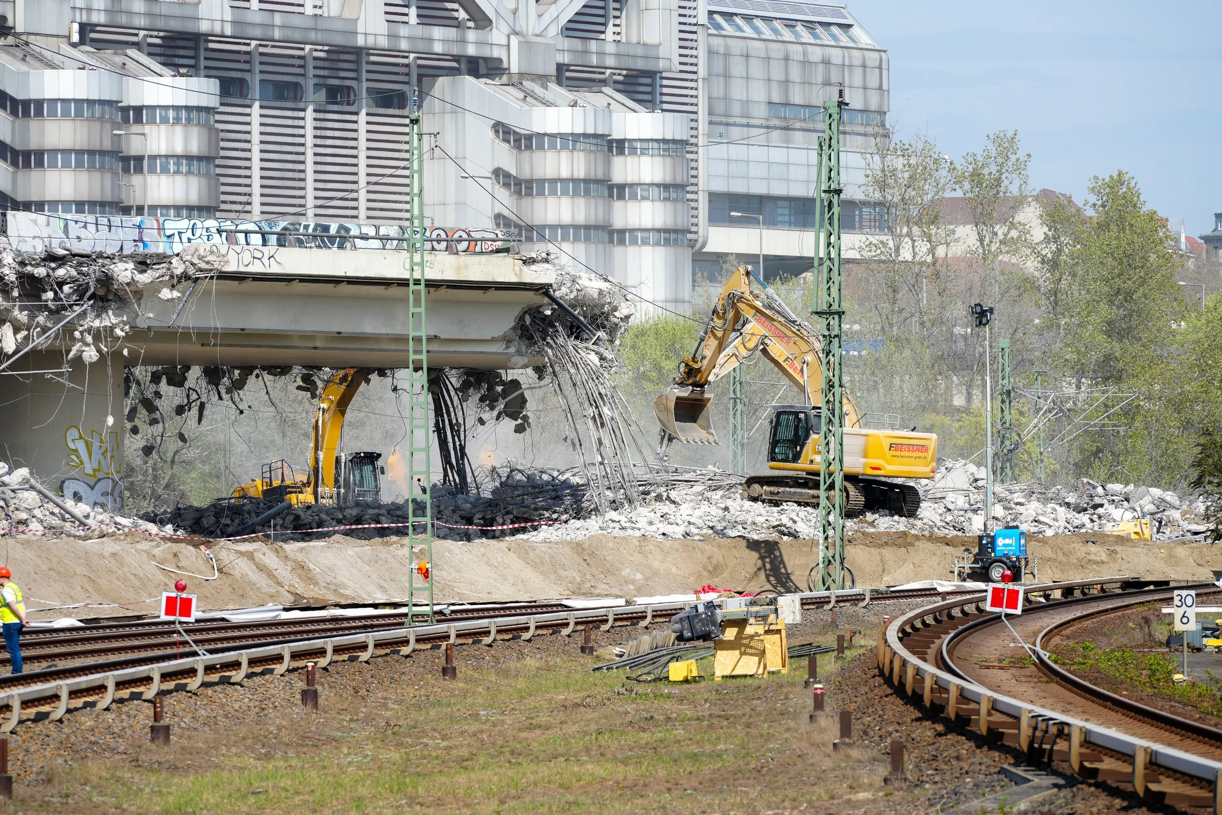 Abriss einer Brücke über Bahngleise mit Baugeräten.