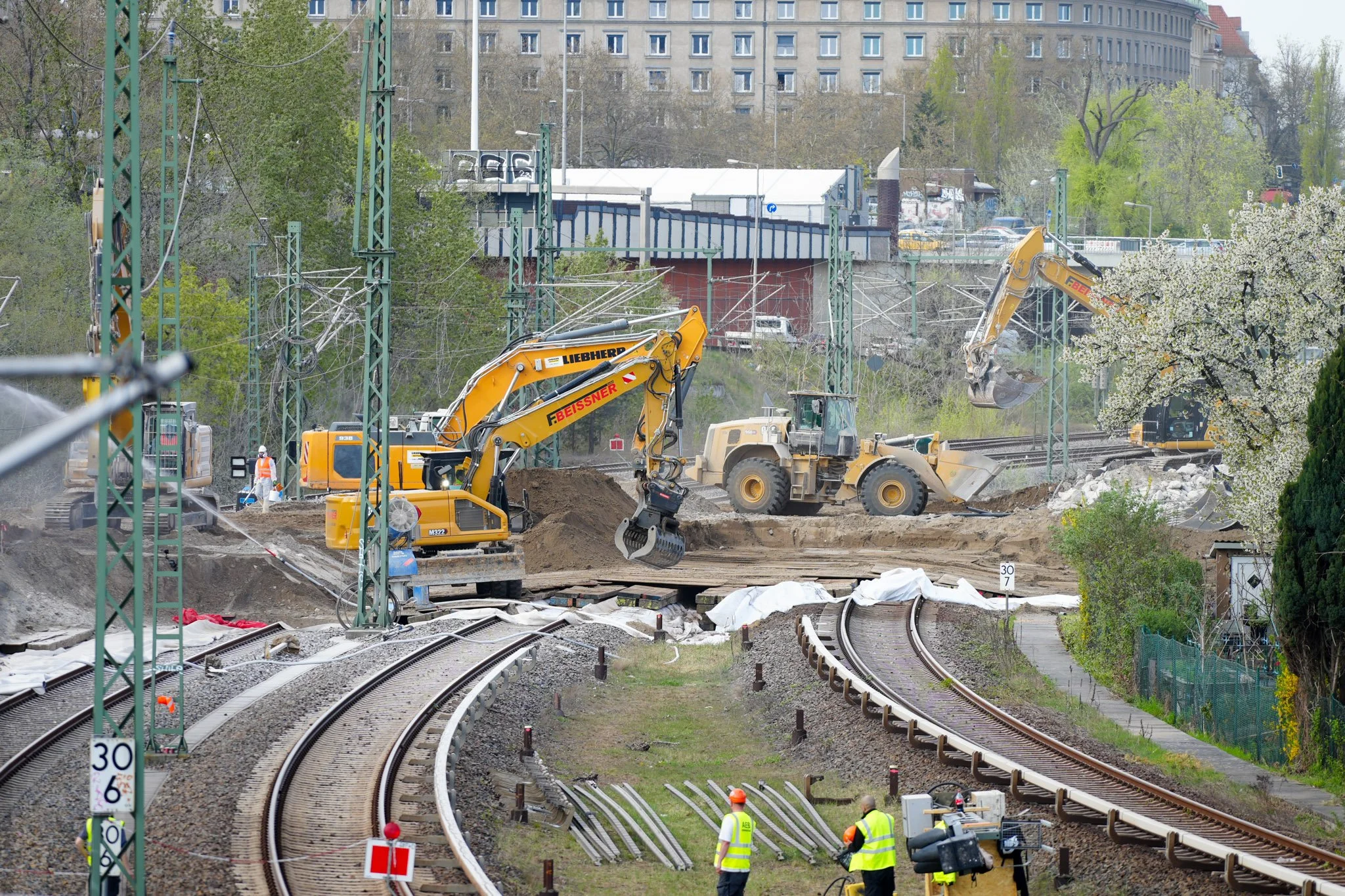 Bauarbeiten an Eisenbahngleisen mit Baggern und Bauarbeitern.