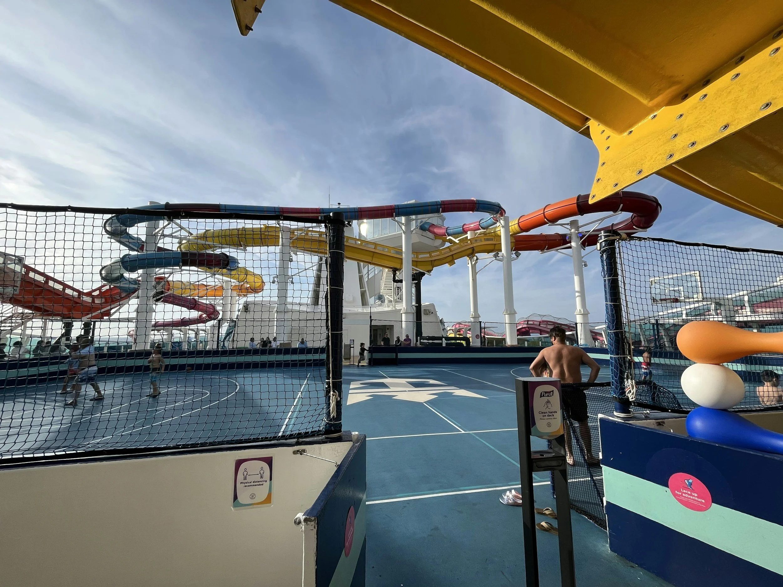 Basketball court on a Royal Caribbean cruise ship with colorful water slides and upper deck attractions in the background