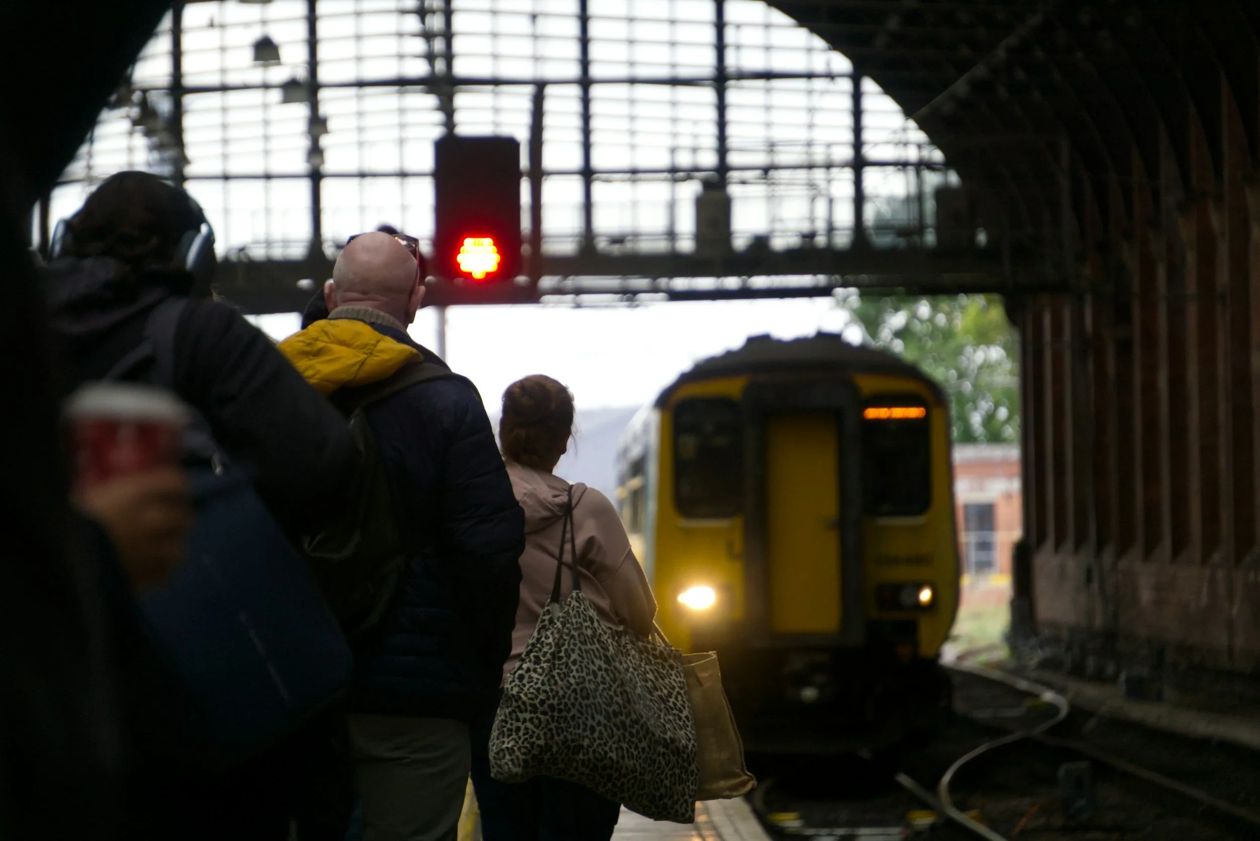 Travelers waiting at a train station representing slower and more intentional travel experiences
