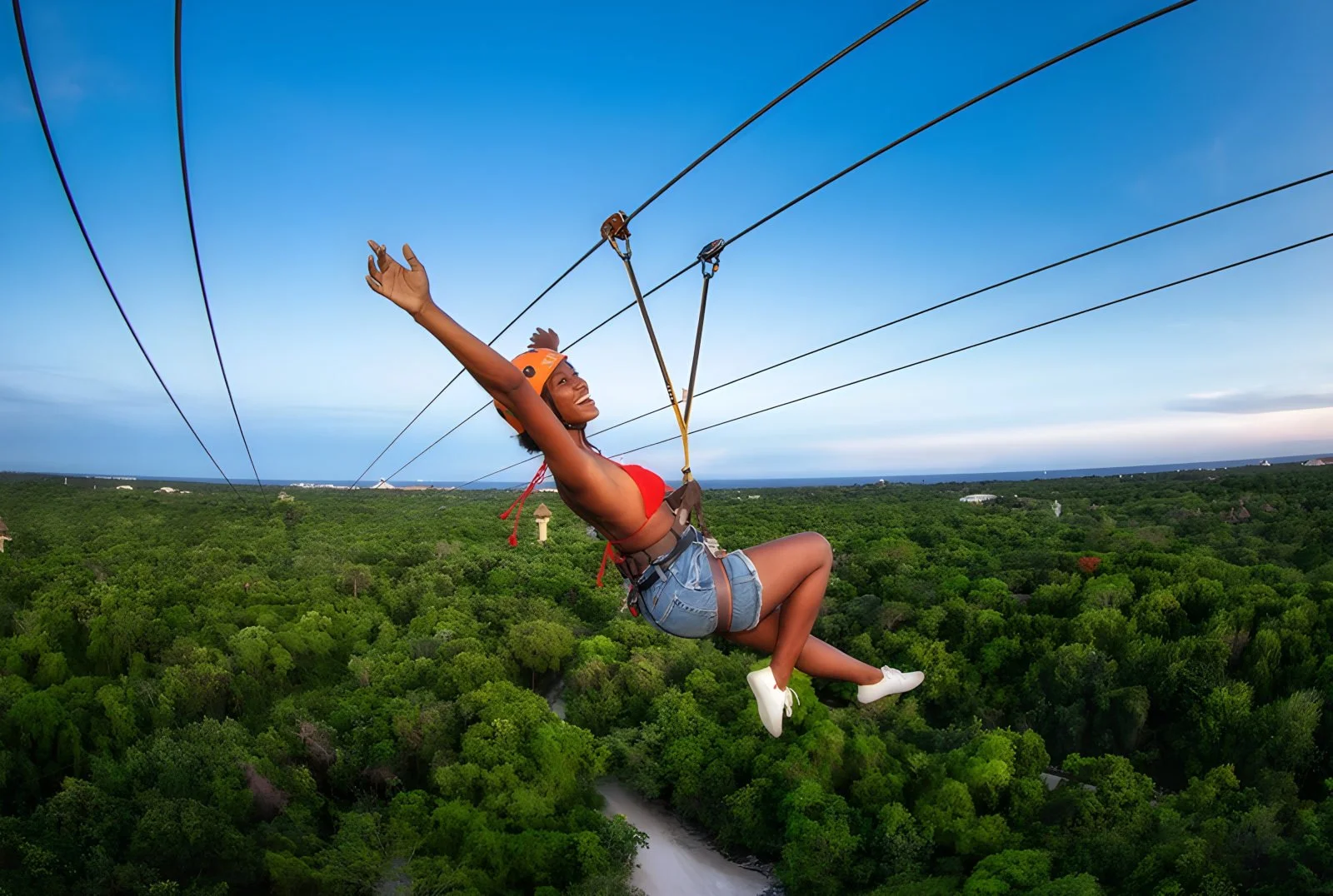 Guest ziplining above the jungle canopy at Xplor Park, illustrating the park’s high-energy adventure activities.