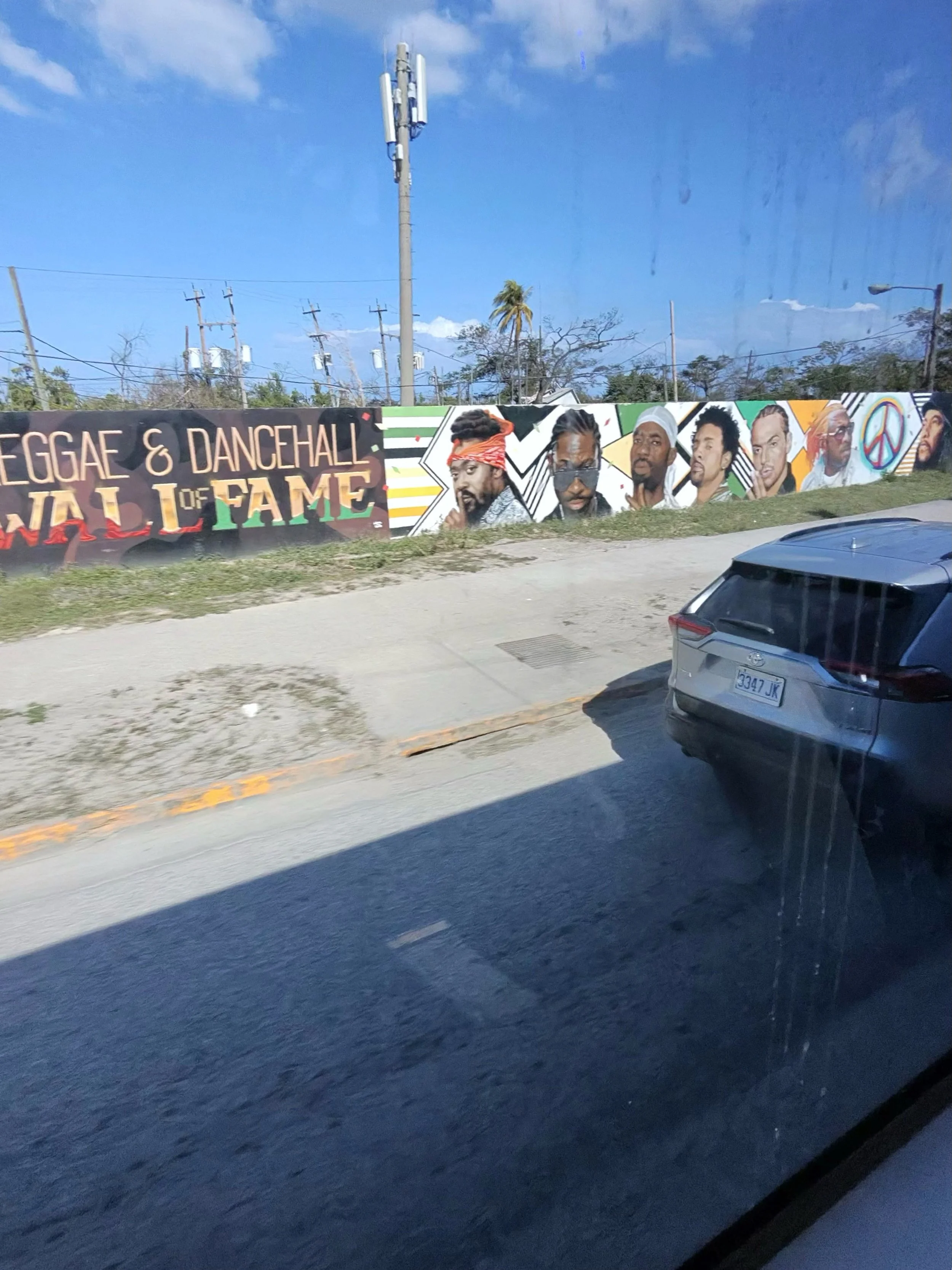 Reggae and Dancehall Wall of Fame mural along a roadway in Montego Bay, Jamaica, featuring portraits of Jamaican music artists.